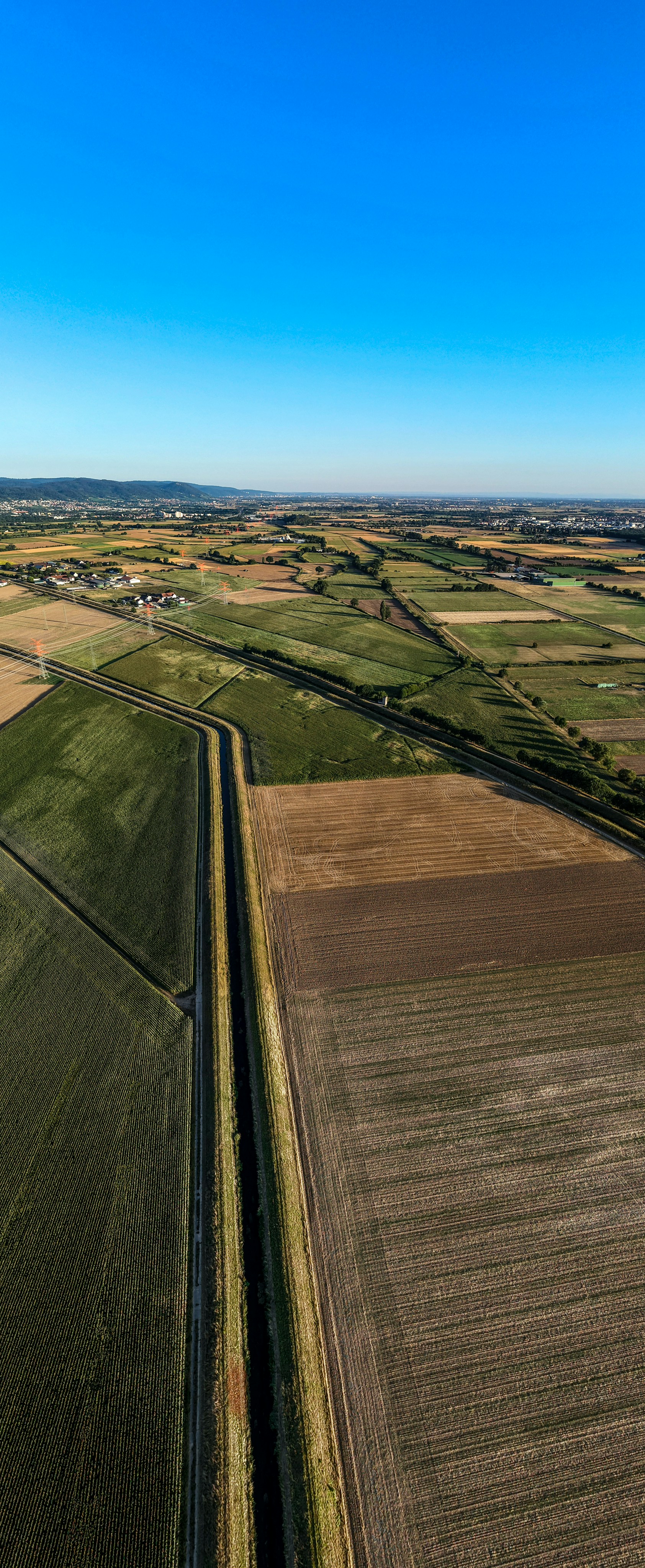 Aerial view of agricultural fields, a canal, and distant town.