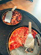 Two deep-dish pizzas with spatulas, one with a slice removed