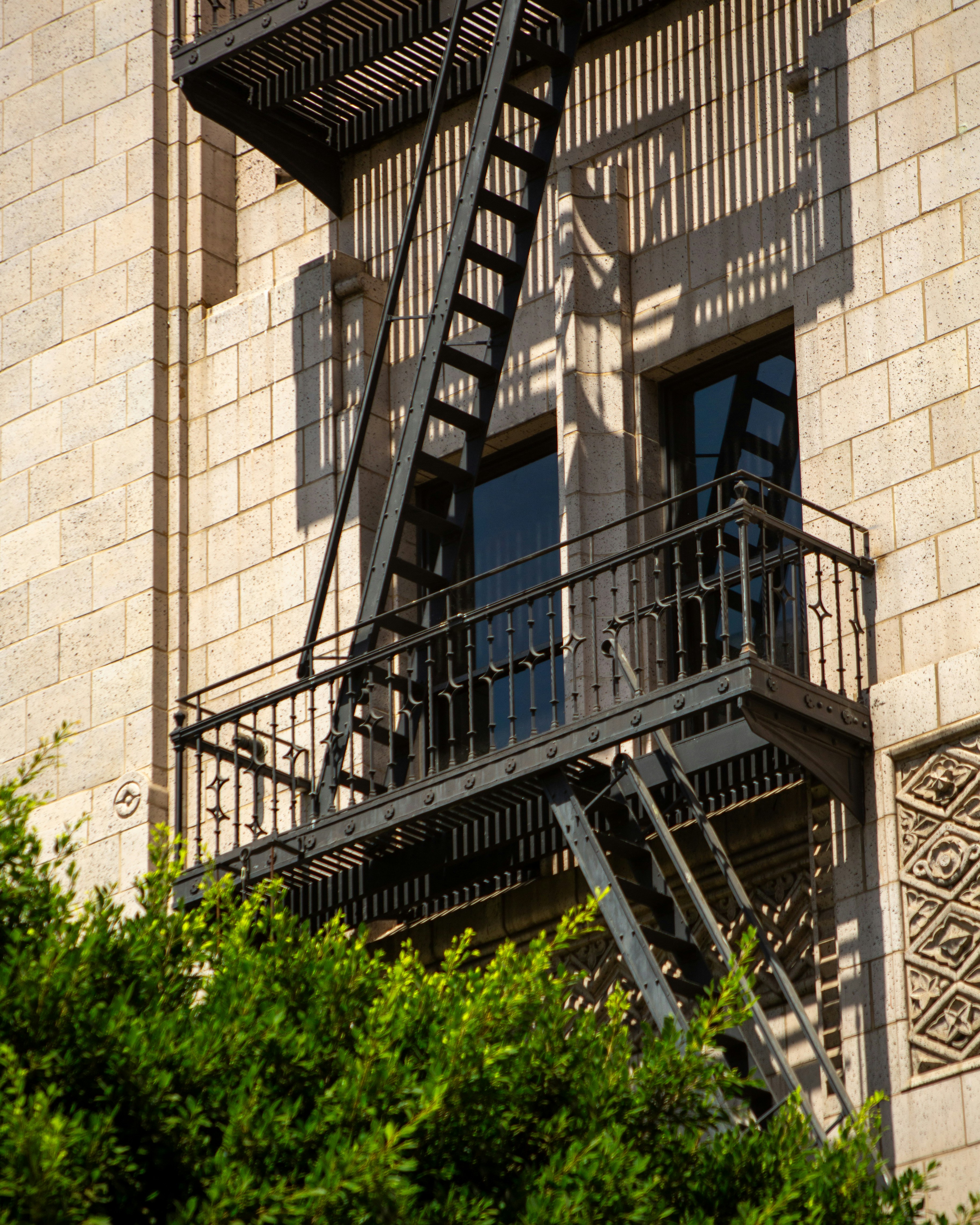 A building with a black fire escape and green trees.