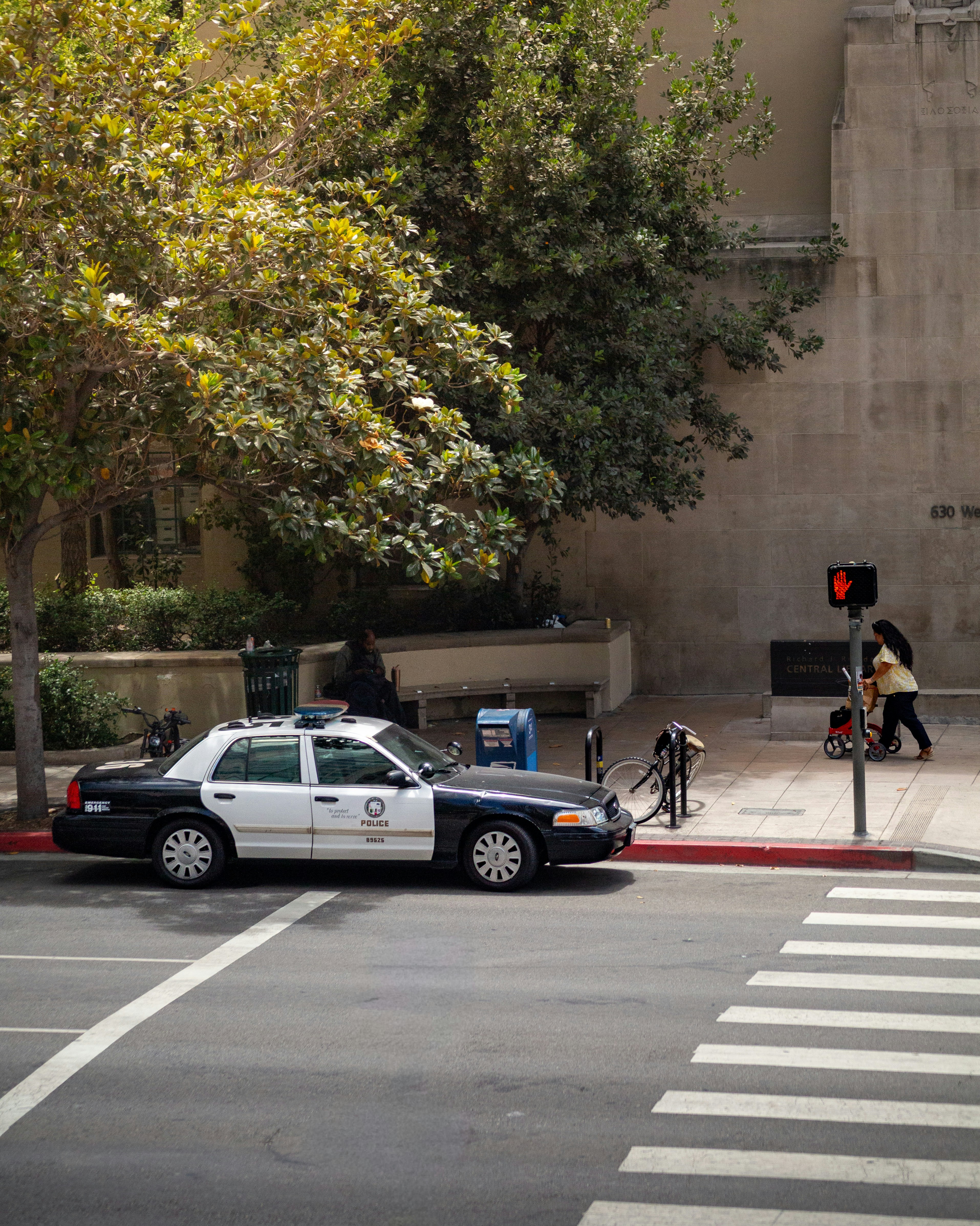 A police car parked beside a crosswalk with a person.