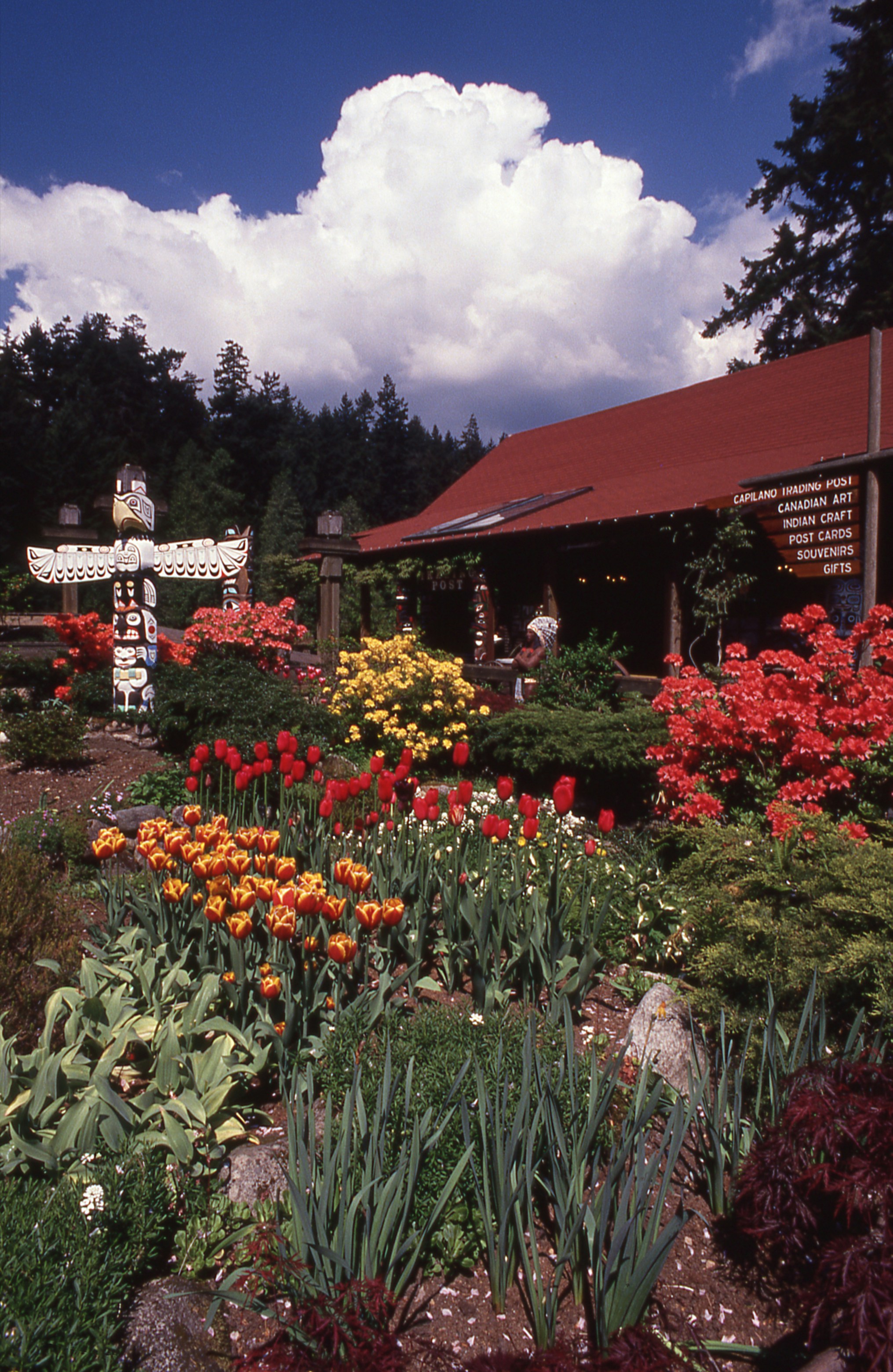 Colorful garden with a red-roofed building and totem pole
