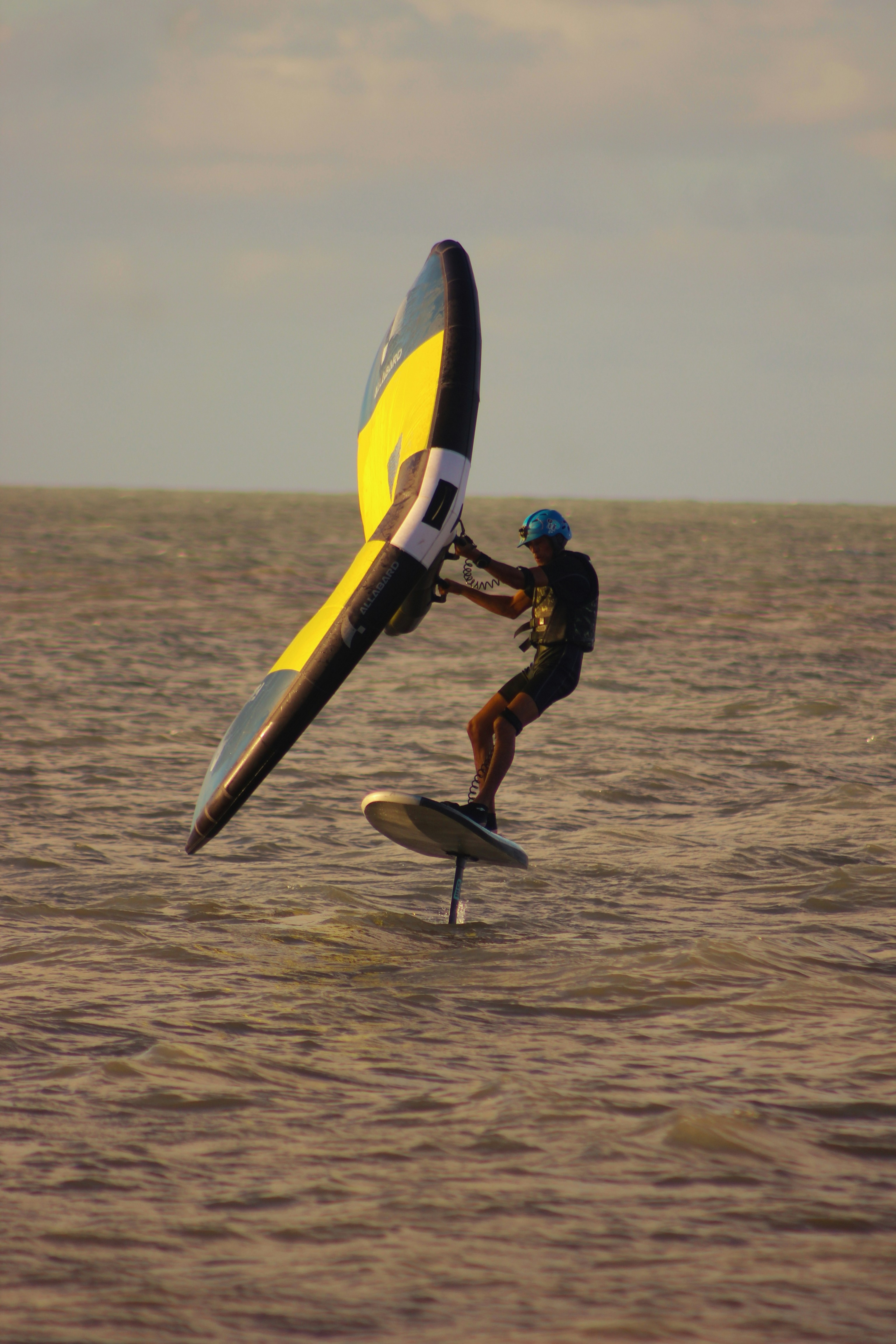 Man wing foiling over calm water.