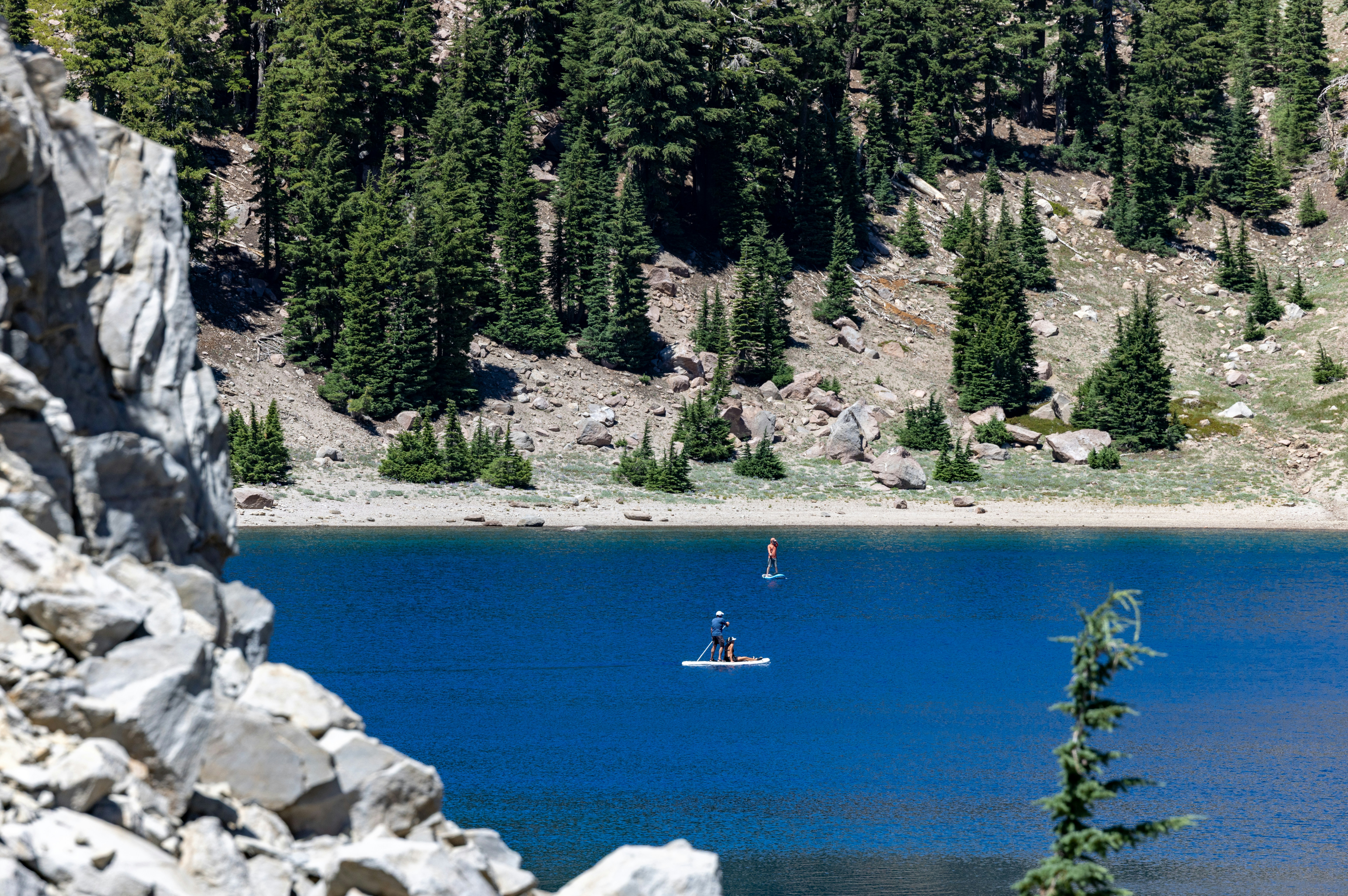 Two people paddleboarding on a blue mountain lake