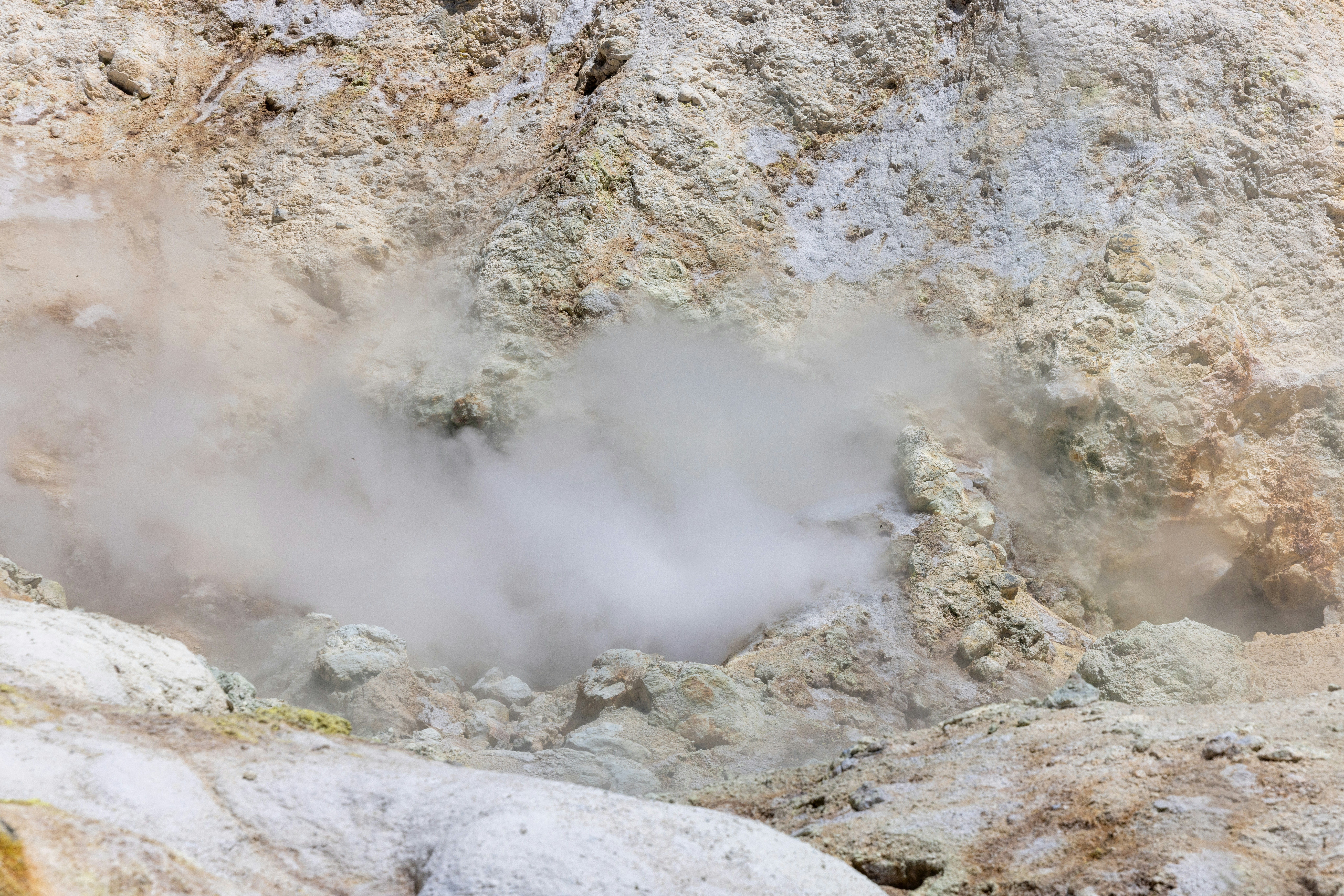 Steam rises from a geothermal vent in a rocky landscape.