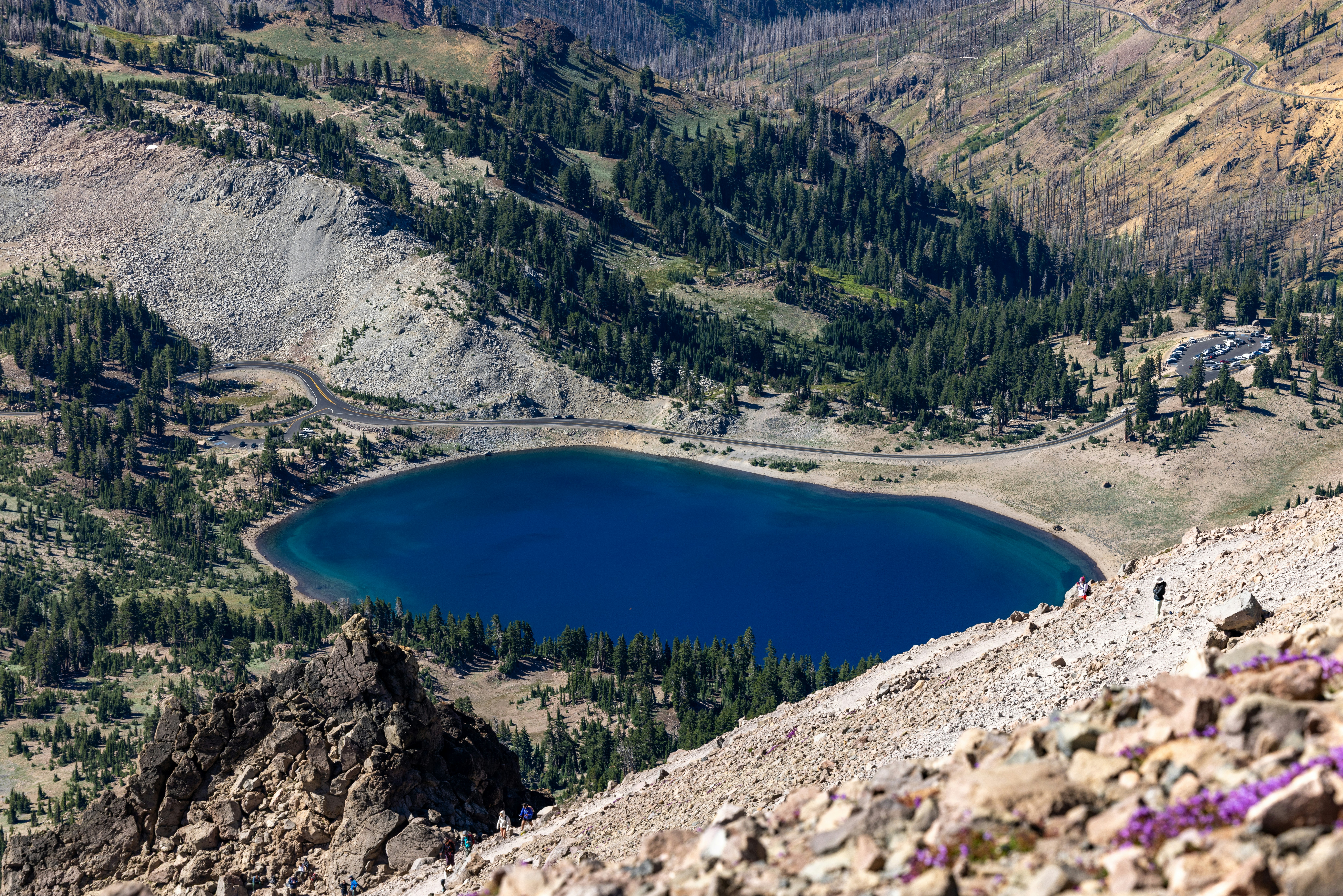 A deep blue lake nestled in a mountainous, forested landscape.