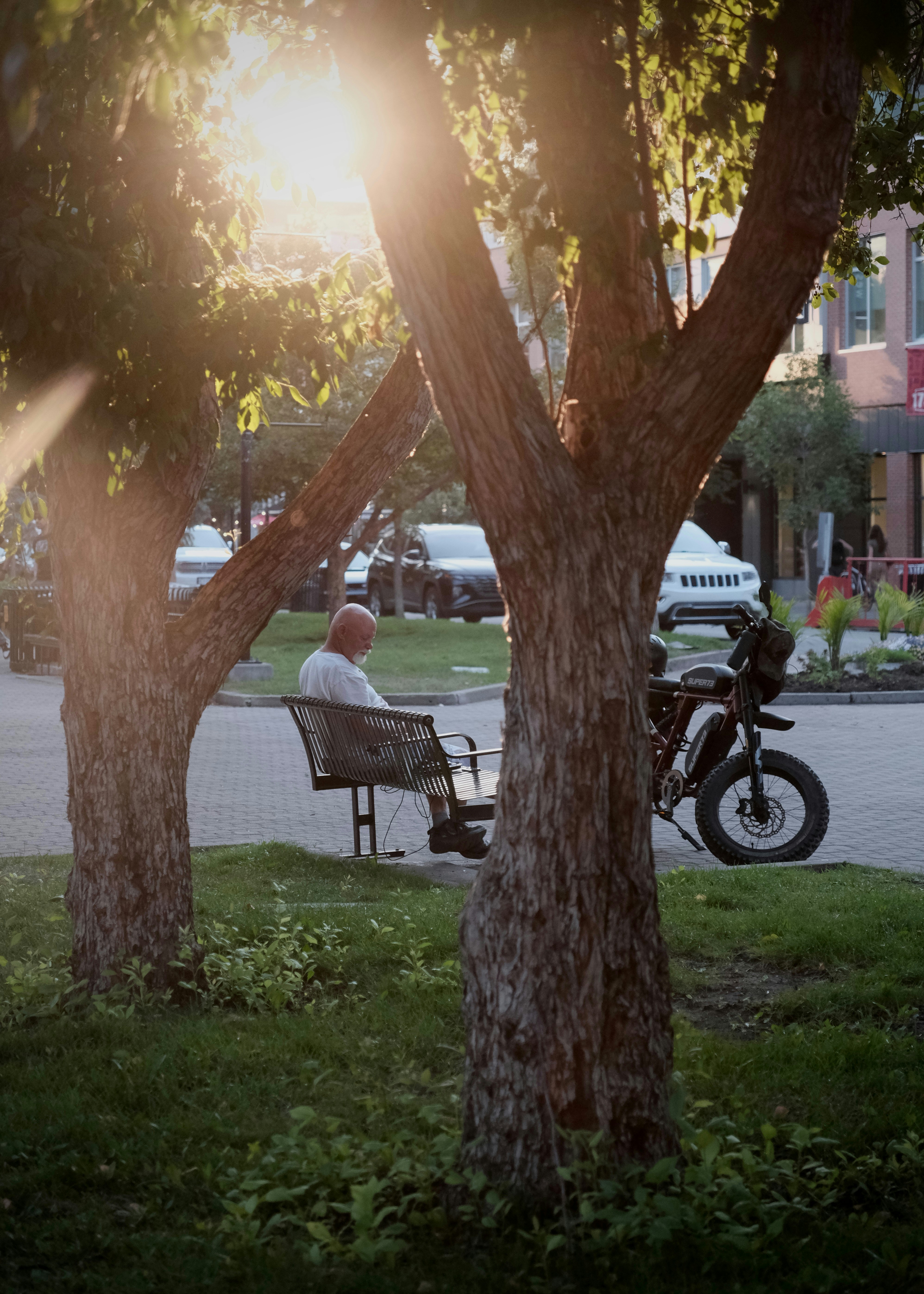 Man sitting on a bench with a motorcycle at sunset