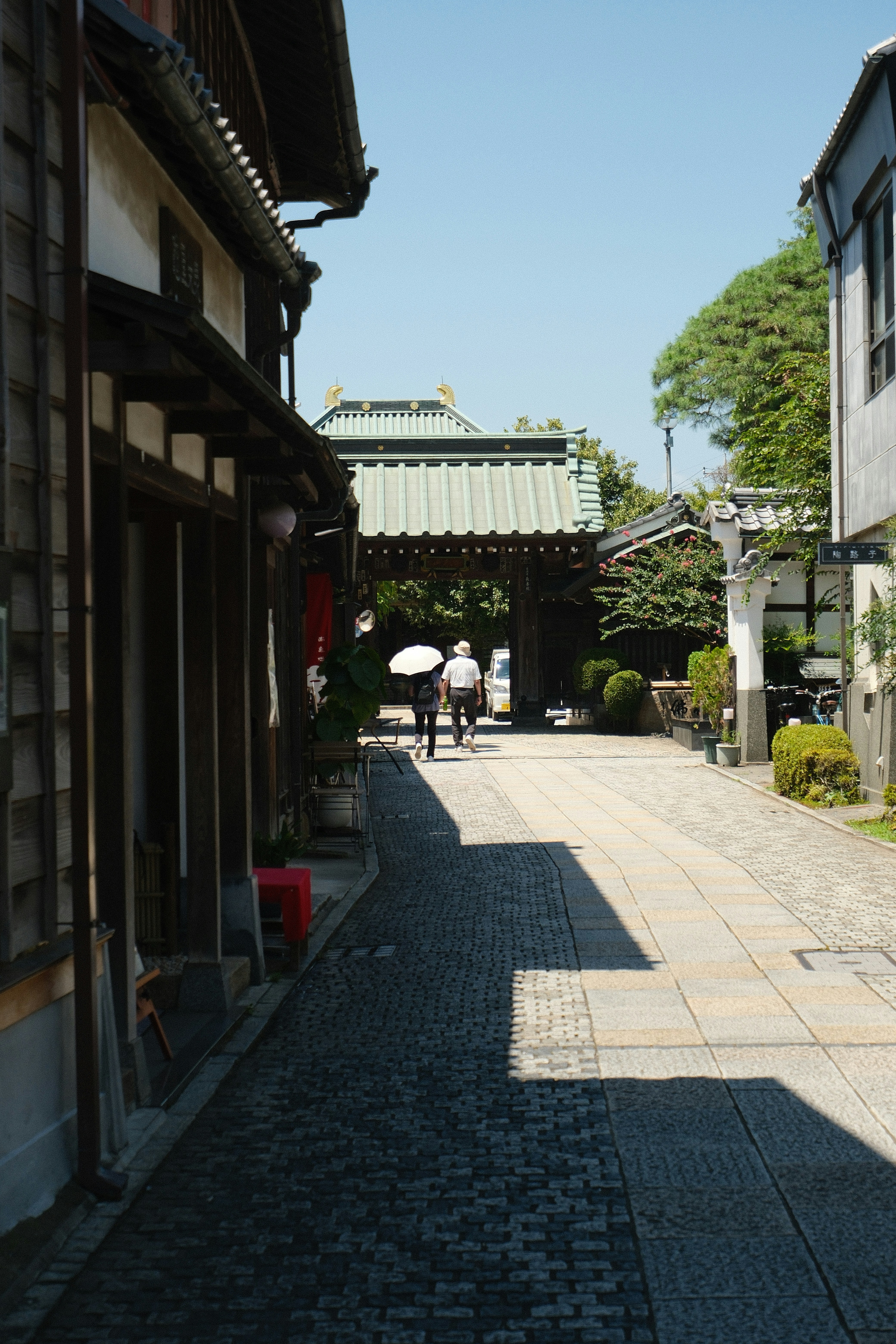 Rue japonaise traditionnelle avec une porte ornée et des gens qui marchent.