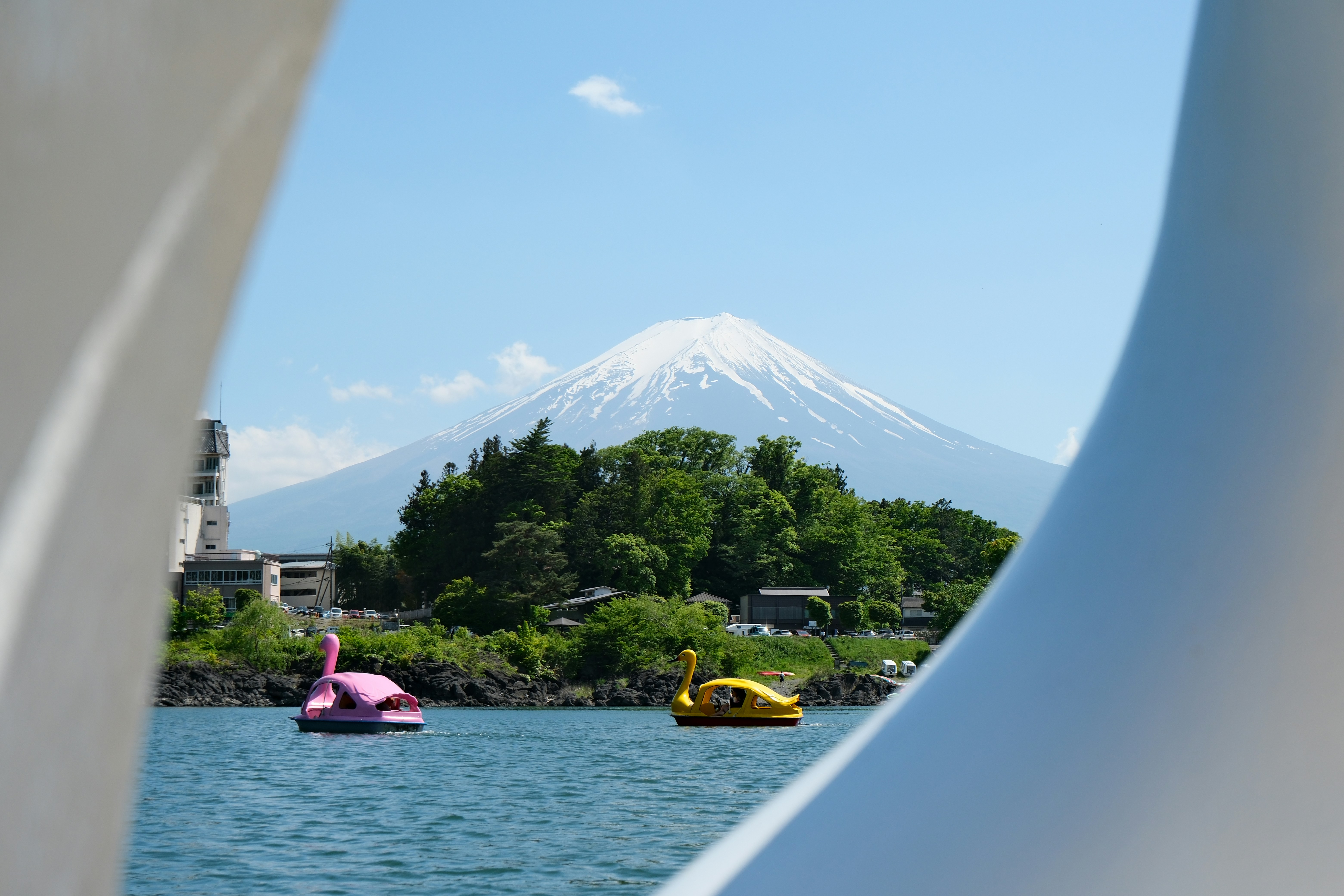 Le mont Fuji enneigé surplombe un lac avec des barques en forme de cygne colorées.