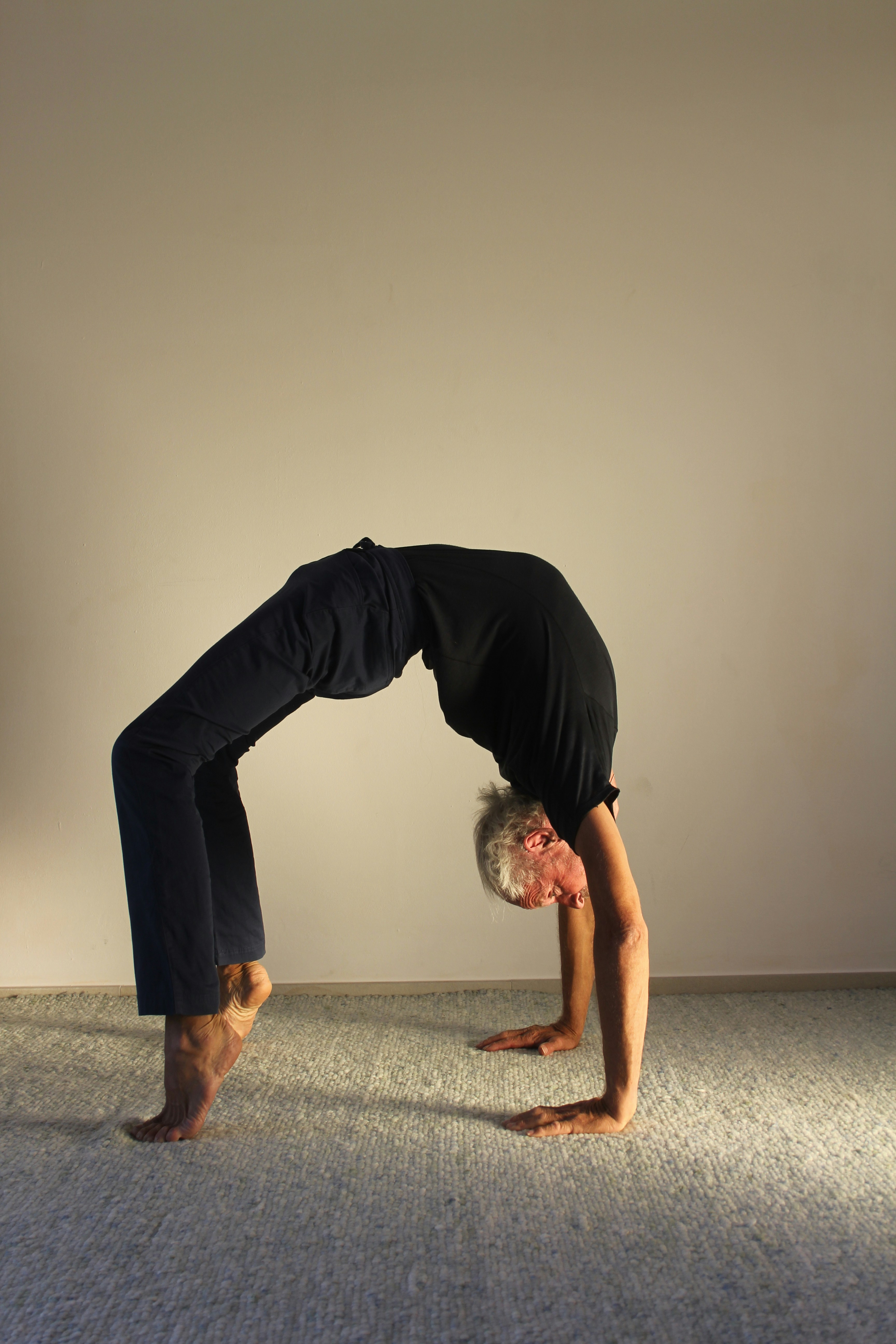 A person with grey hair performs a yoga bridge pose