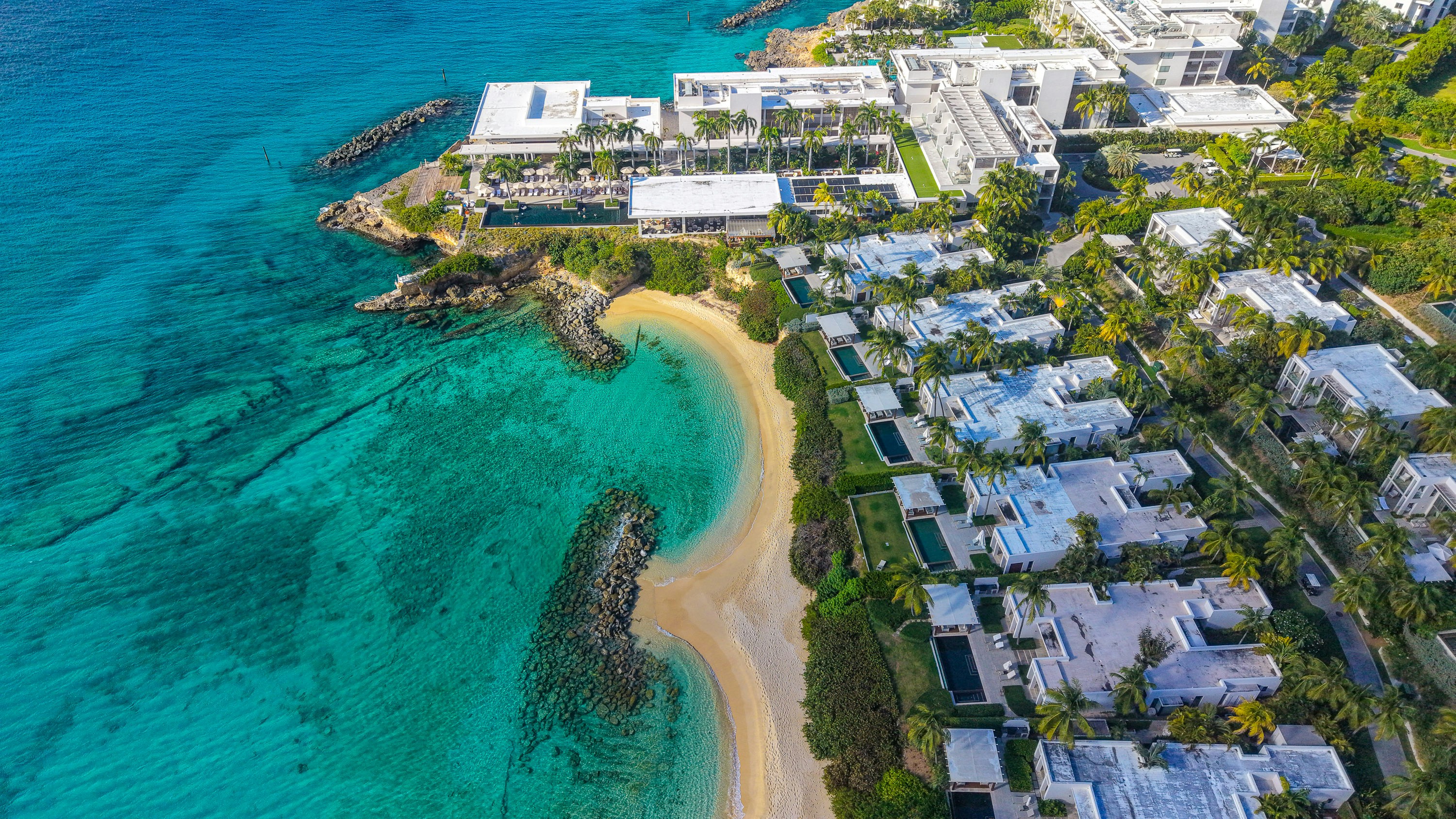 Luxury resort buildings line a stunning turquoise beach