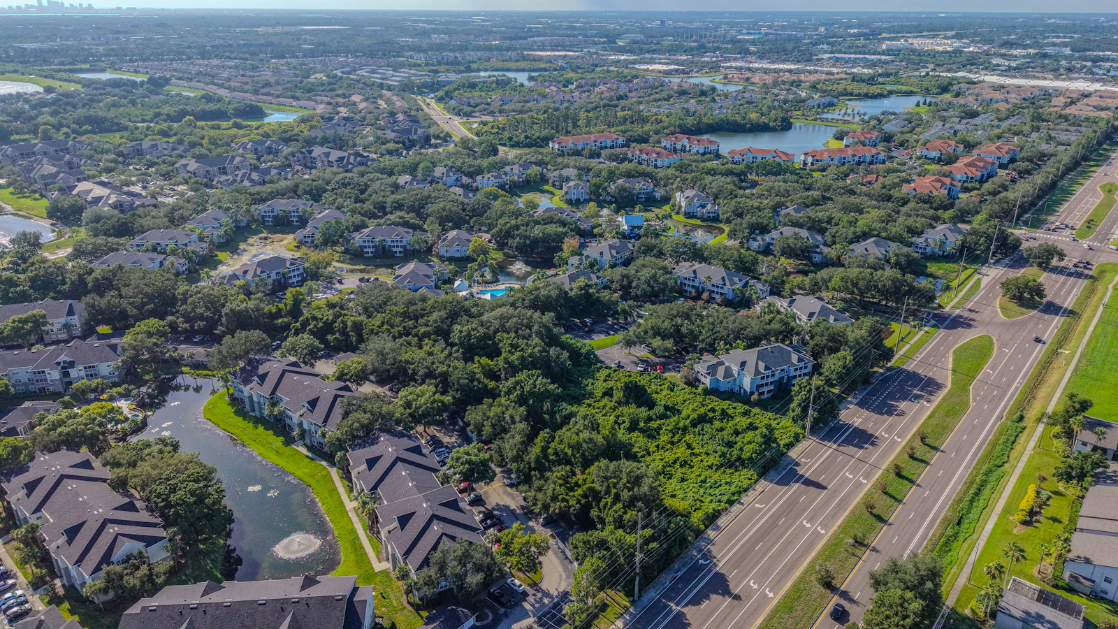 Aerial view of suburban homes, roads, trees, and water.