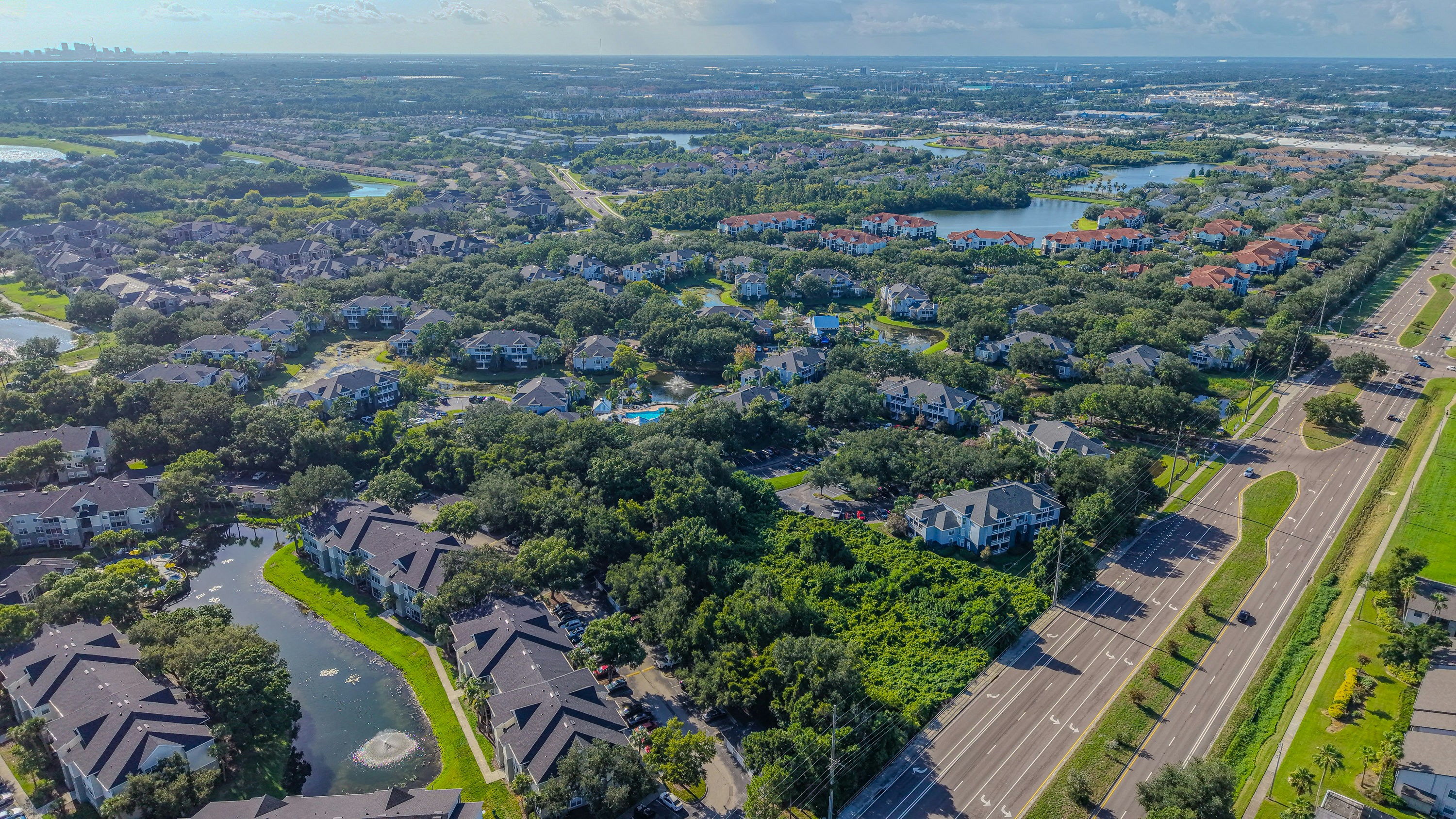 Suburban landscape with residential buildings, roads, green spaces, and lakes