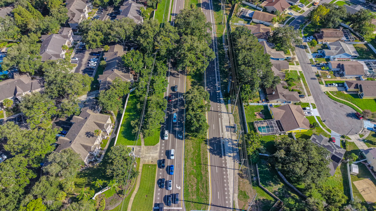Traffic moving along a suburban arterial seen from above, the drive time that decides how many stops fit in a window