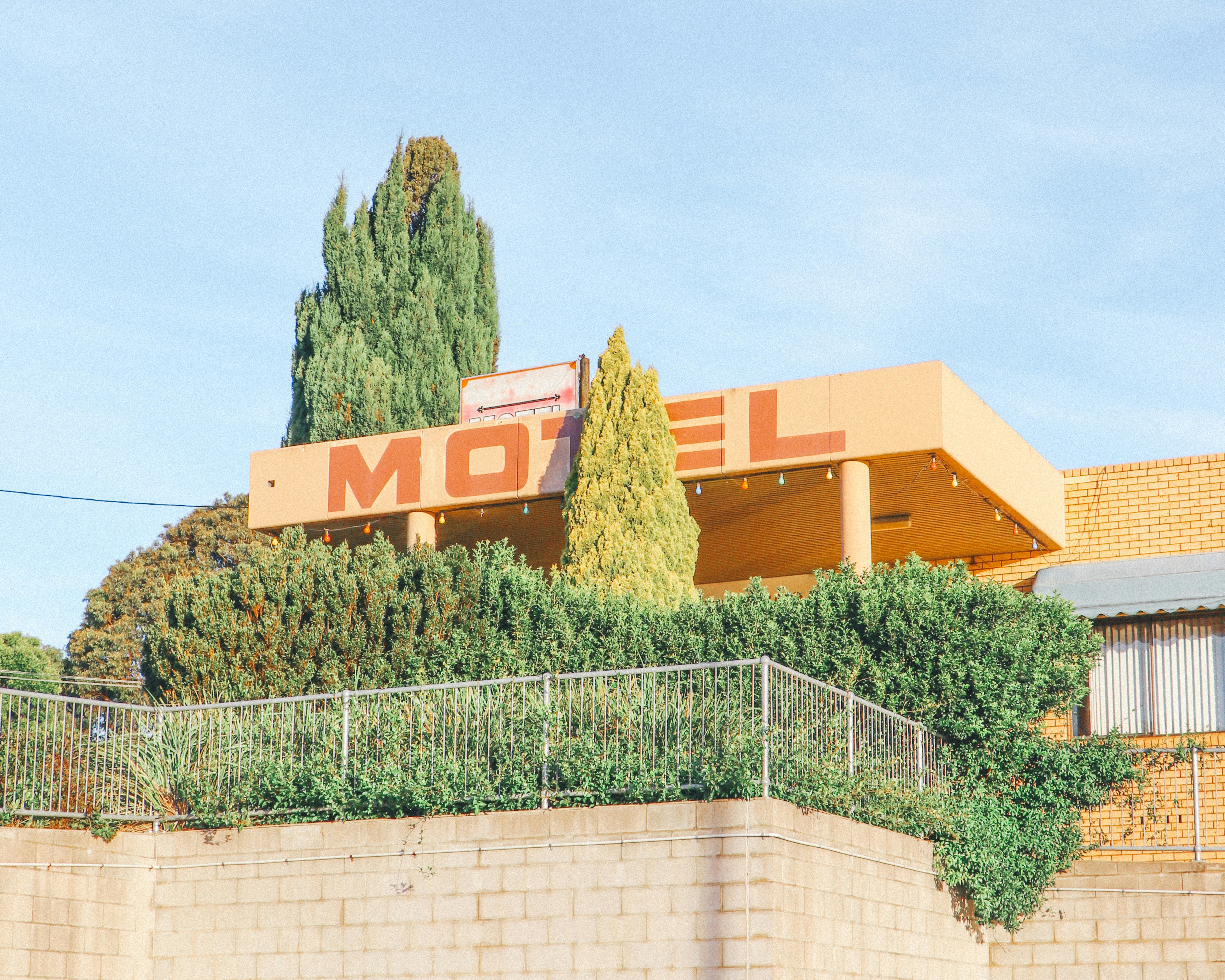 A motel sign on a building surrounded by green trees.