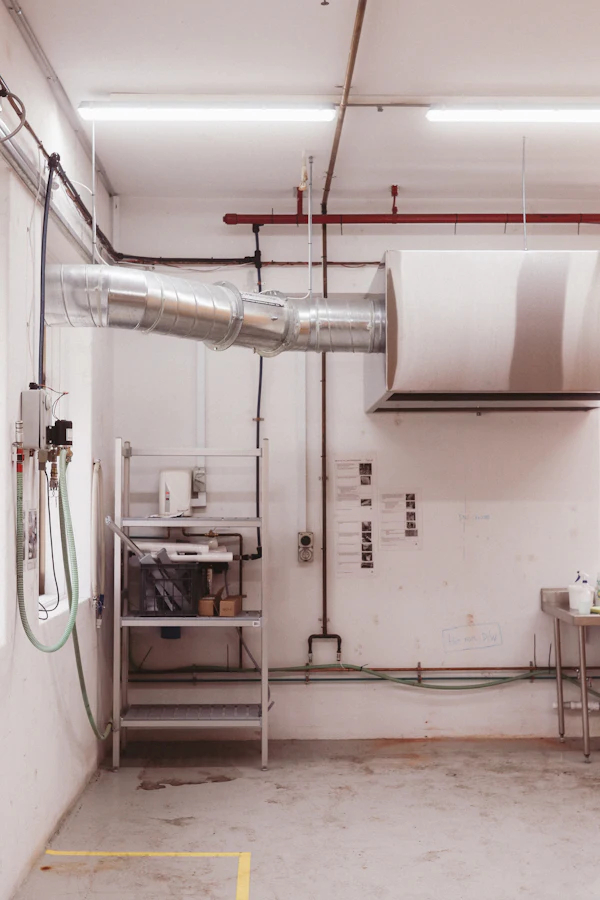 Industrial ventilation ducts and red pipes over a work area
