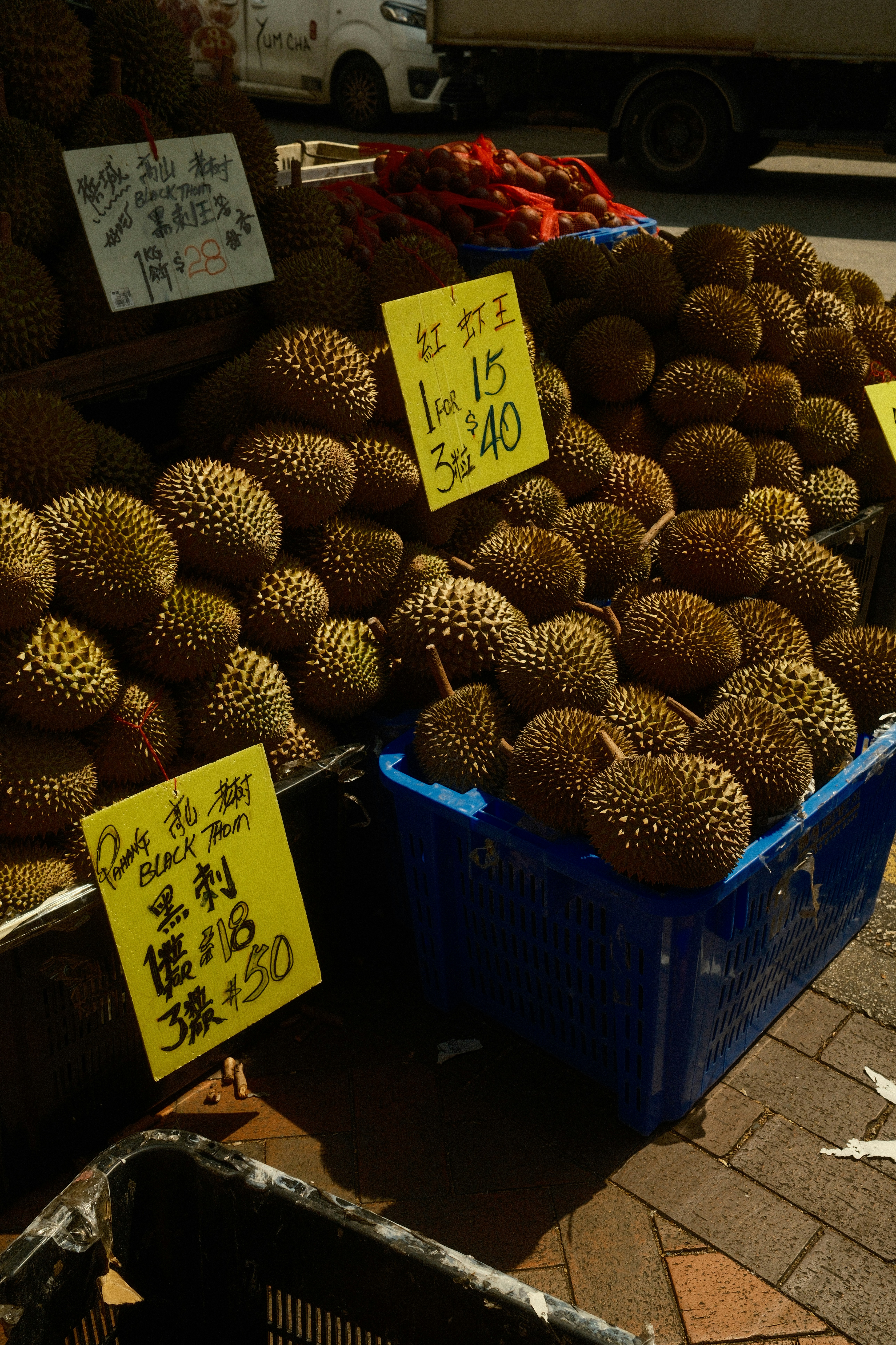 Piles of durian fruit with price tags at a market.
