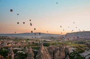 Hot air balloons float over unique rock formations at sunrise