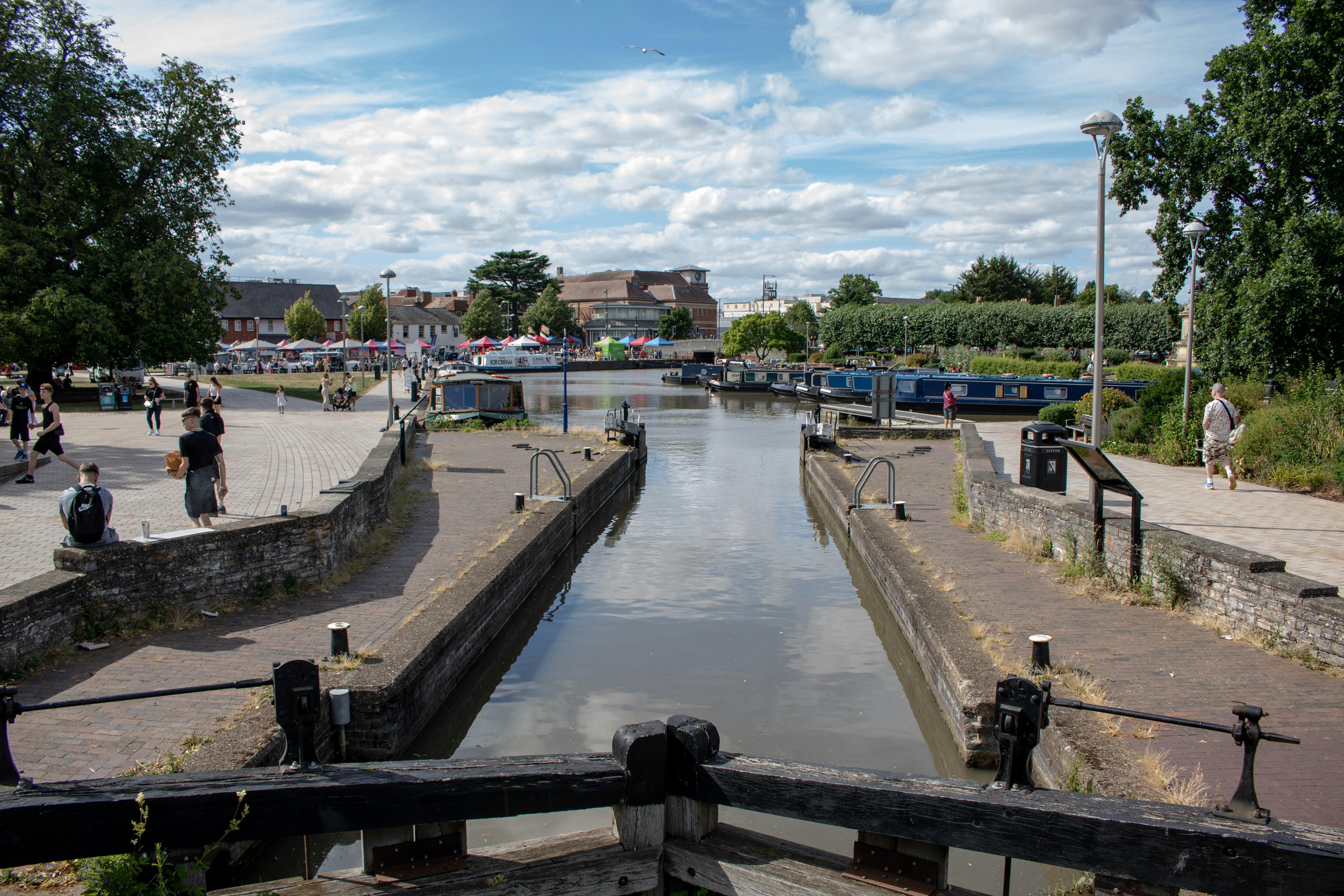 Canal lock with people and boats under a cloudy sky - historic dams and canals
