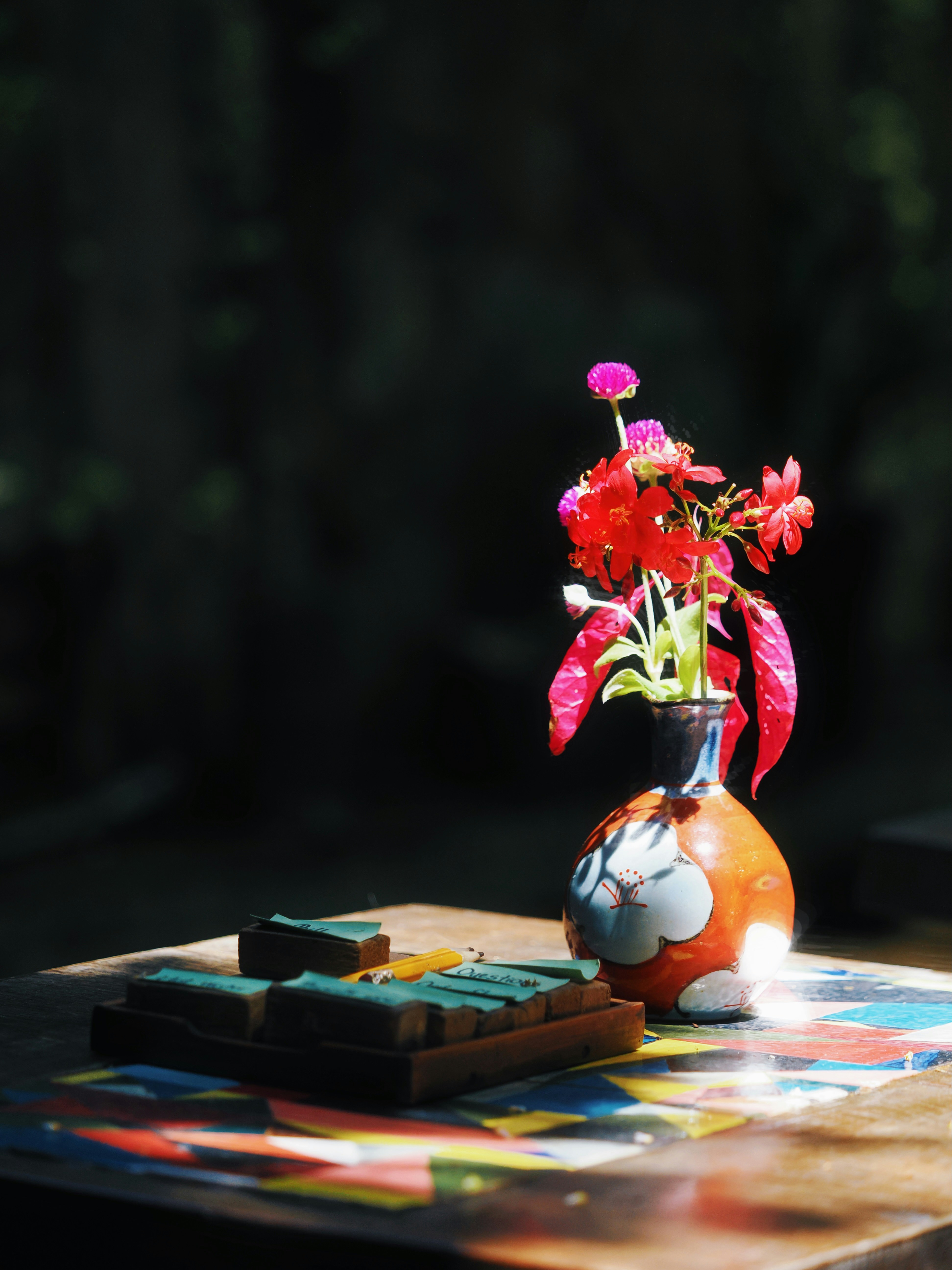 Red flowers in a cat-shaped vase on a colorful table.