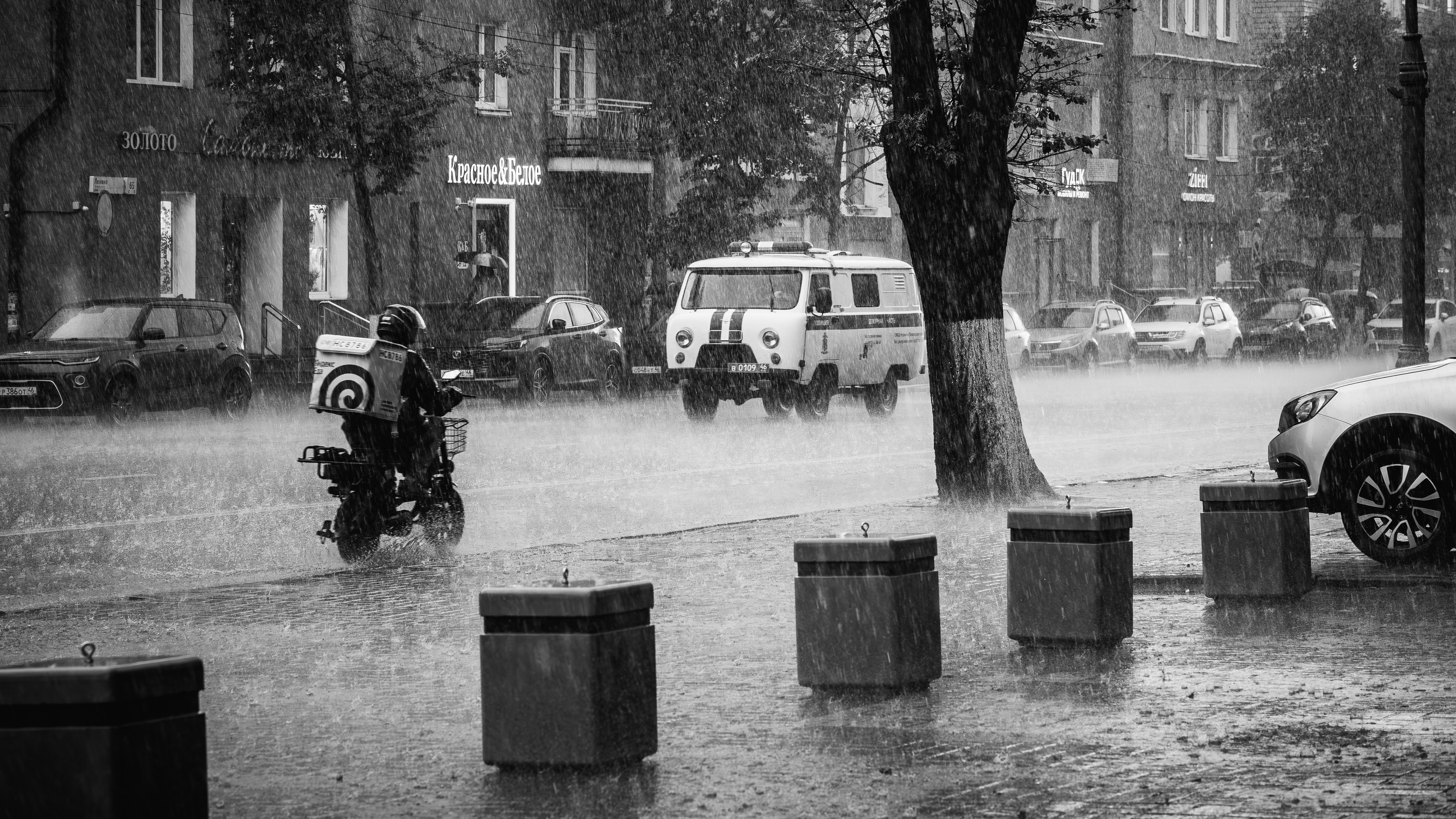 激しい雨の中の街中のスクーターライダー。