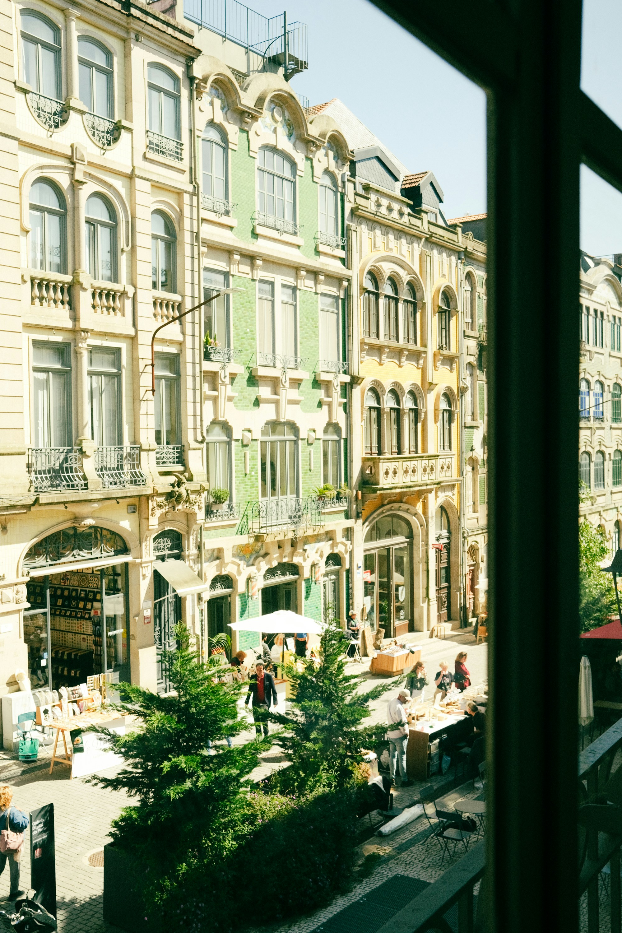 Verzierte Gebäude säumen eine belebte Straße mit Menschen und Bäumen