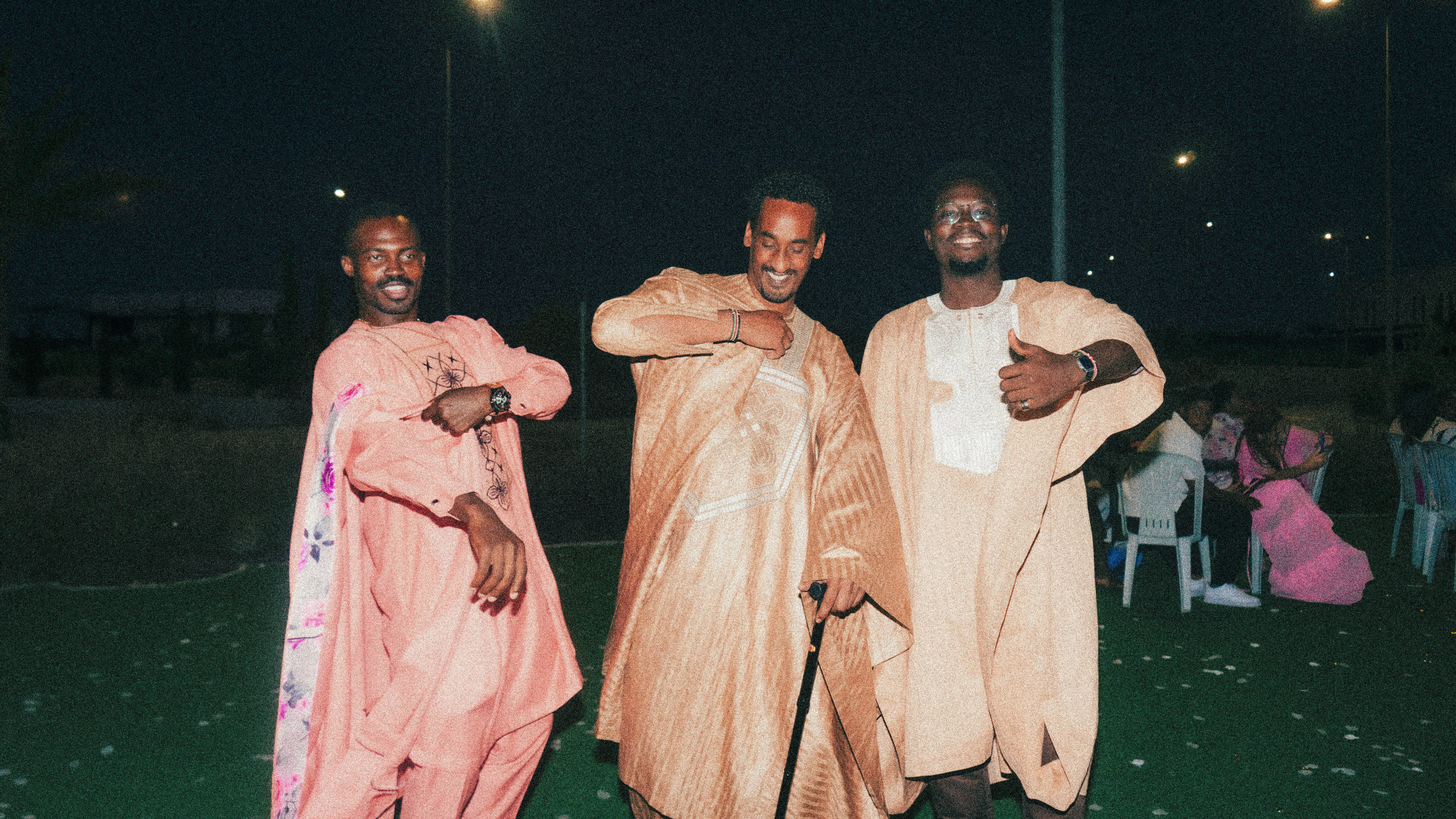 Three men in traditional robes dancing outdoors at night.