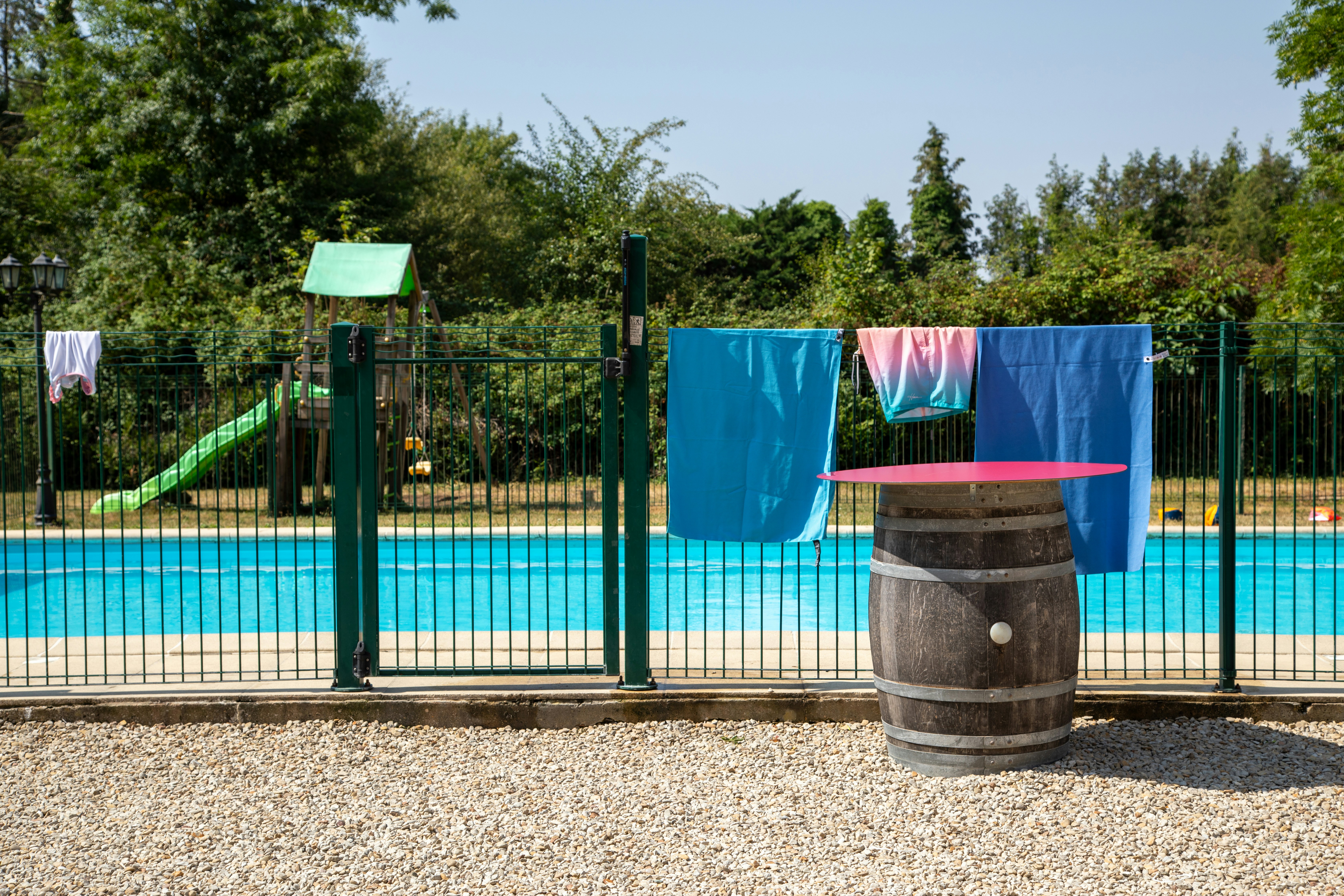 Colorful towels drying on a fence by a swimming pool.