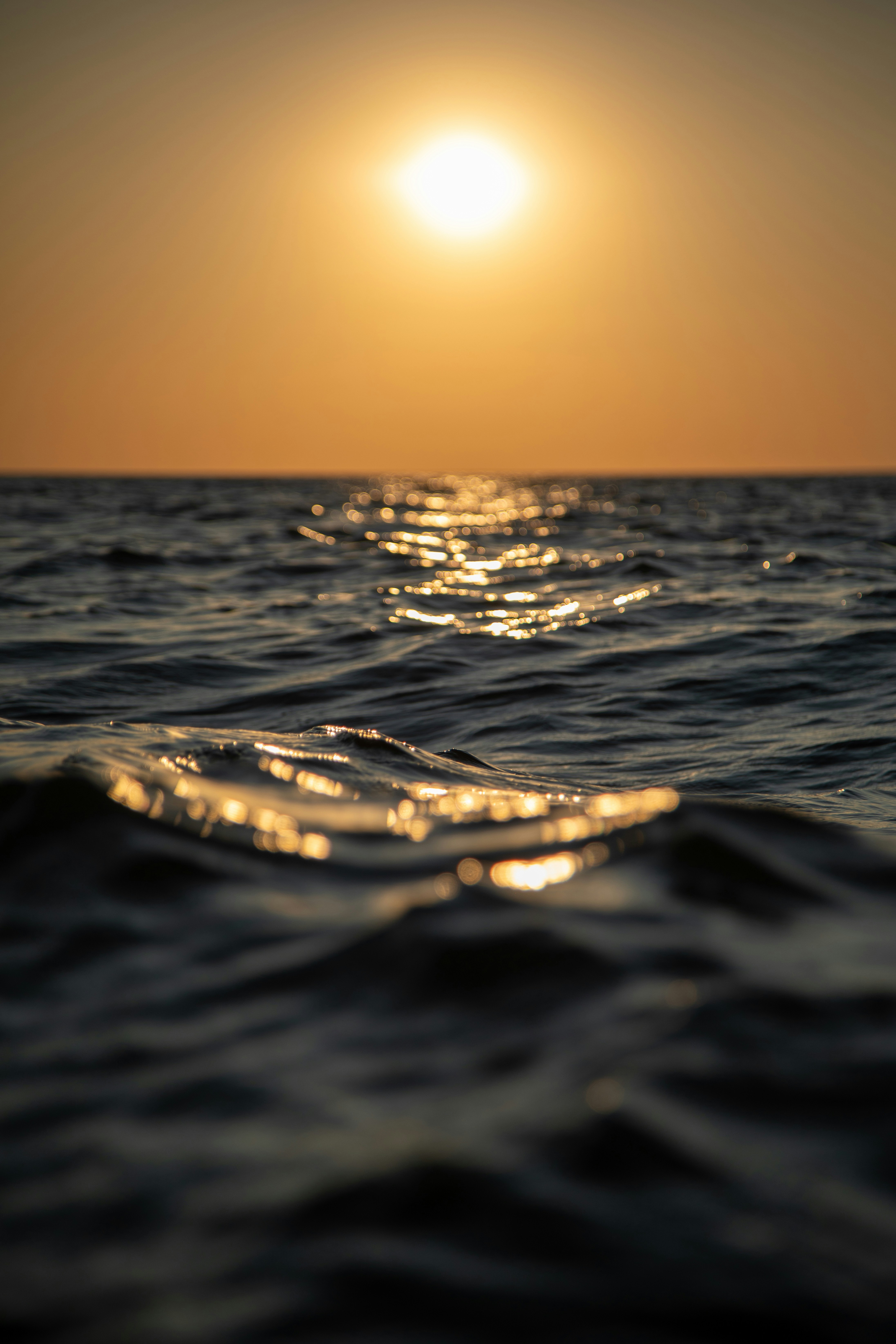 Sunset over the ocean with sun reflecting on waves.