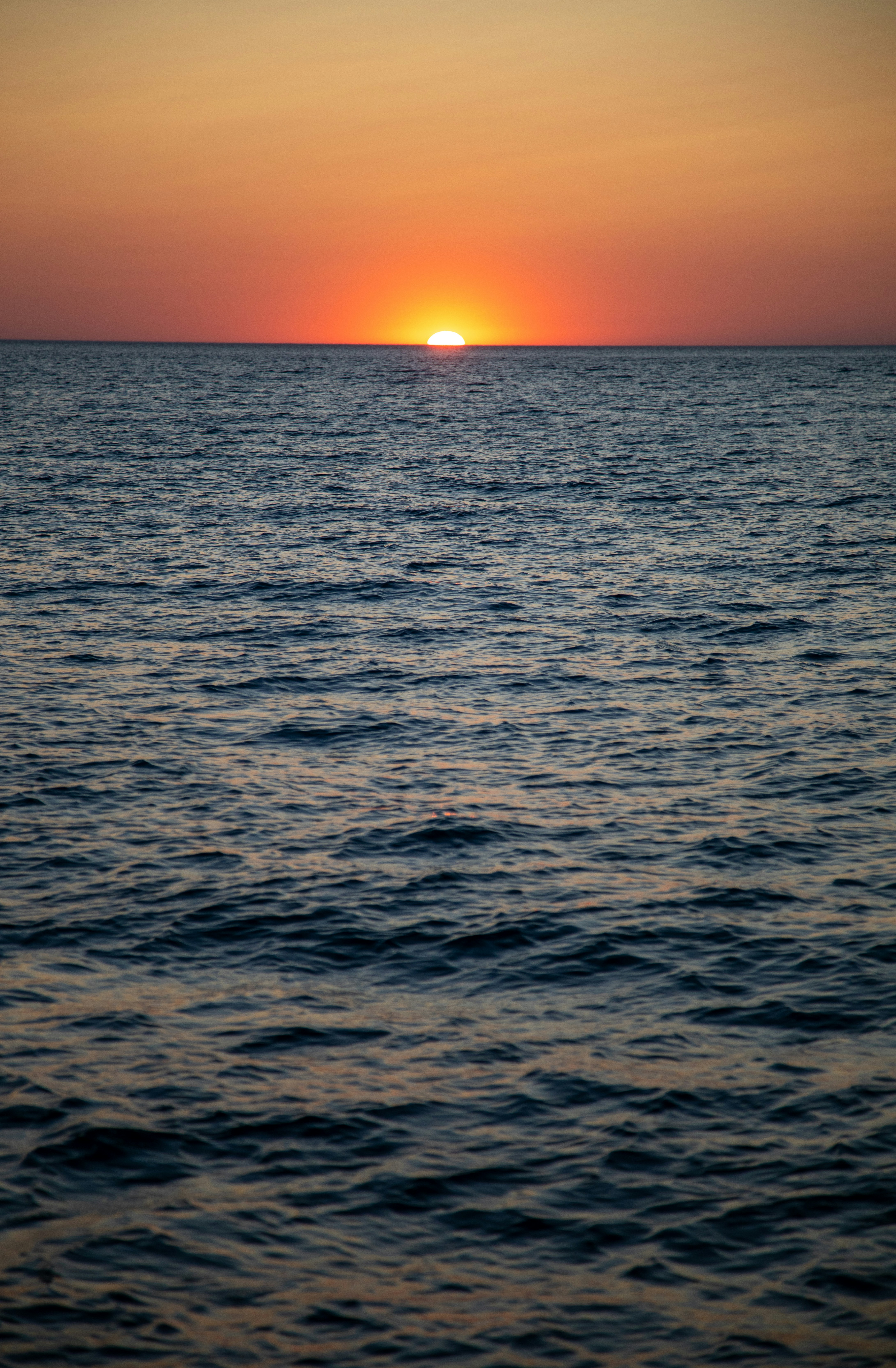 Vibrant orange sunset over the dark blue ocean.