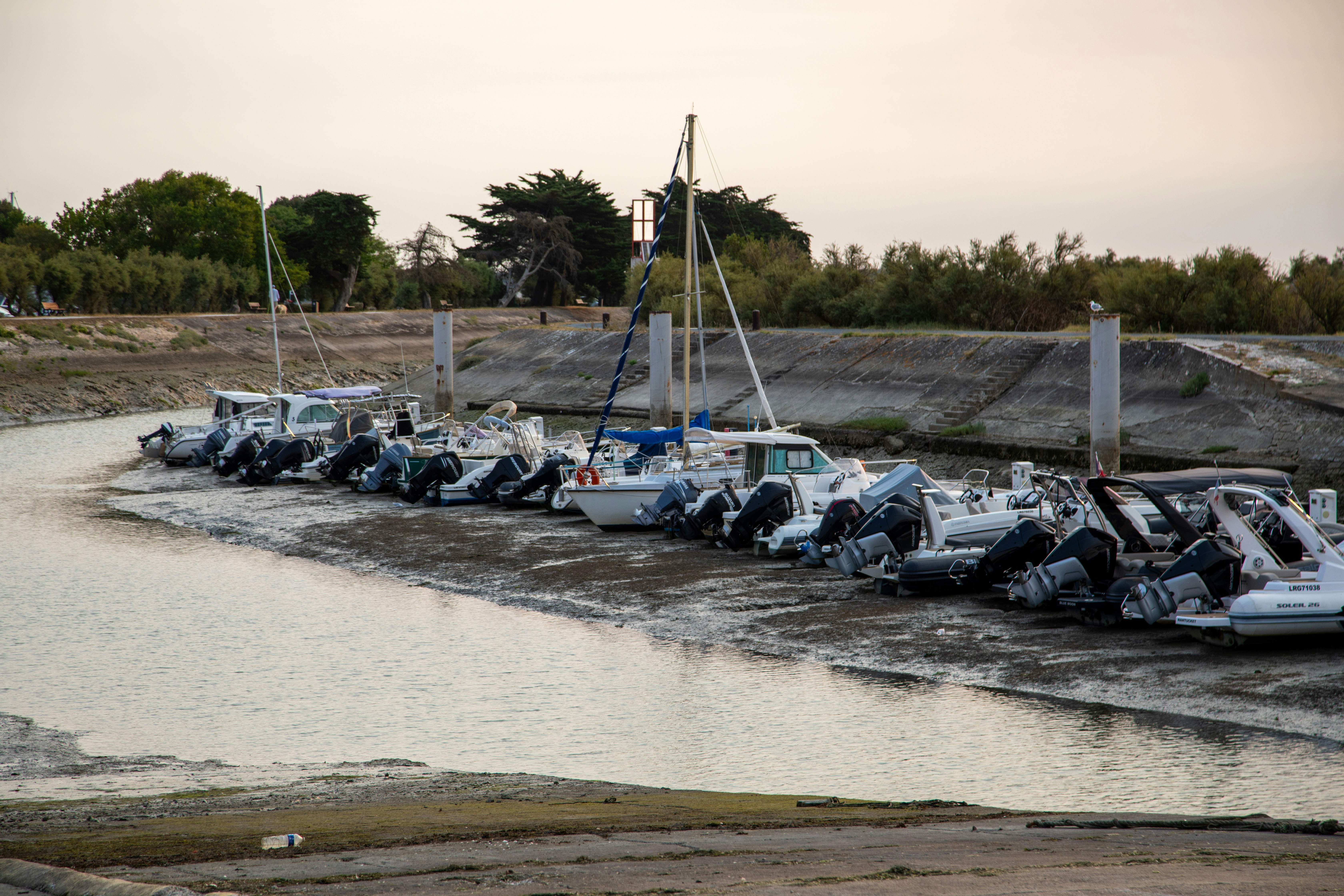 Boats docked in a muddy channel at low tide.