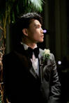 A man in a tuxedo with a boutonnière looks away.
