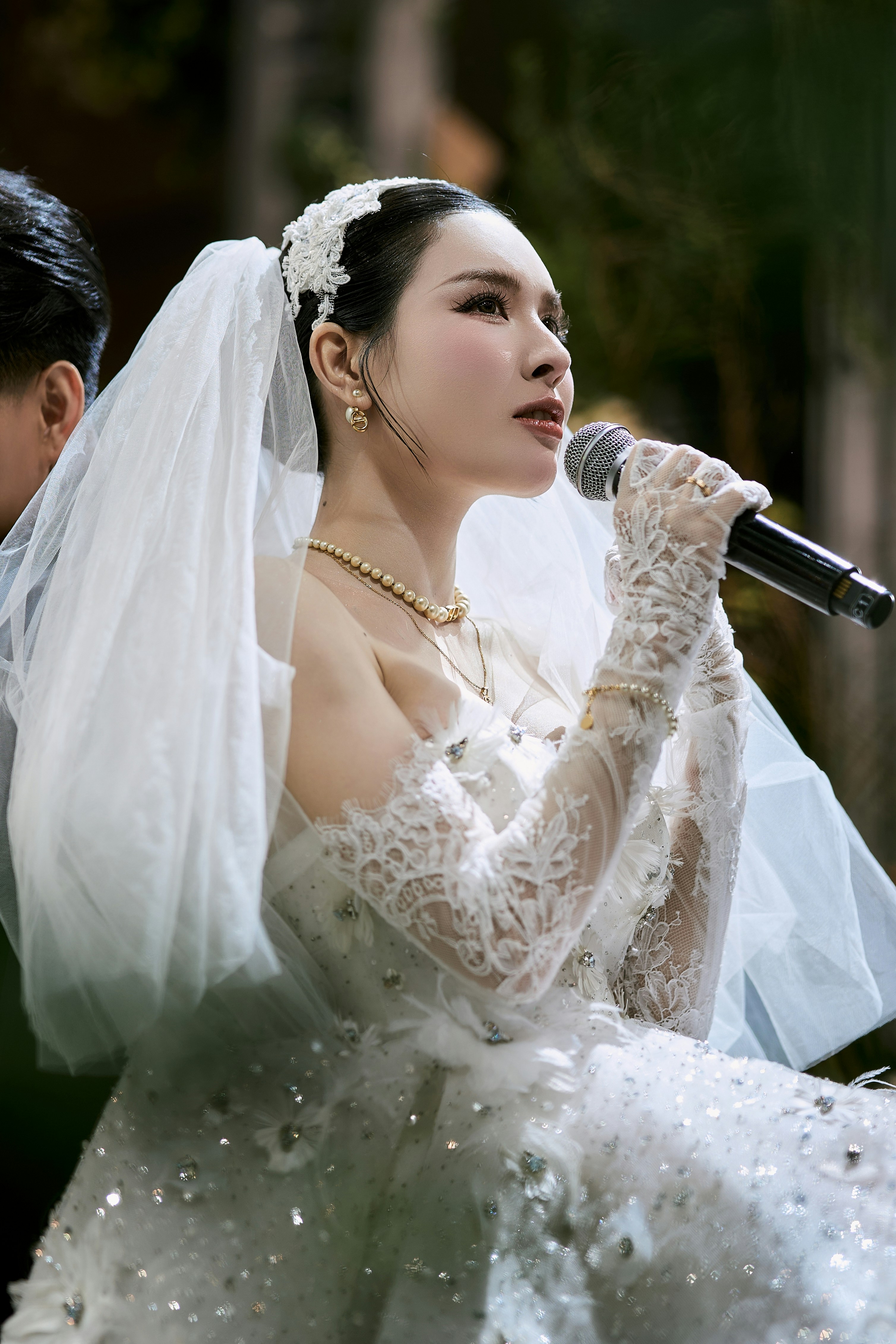 Bride in white wedding dress and veil singing with microphone