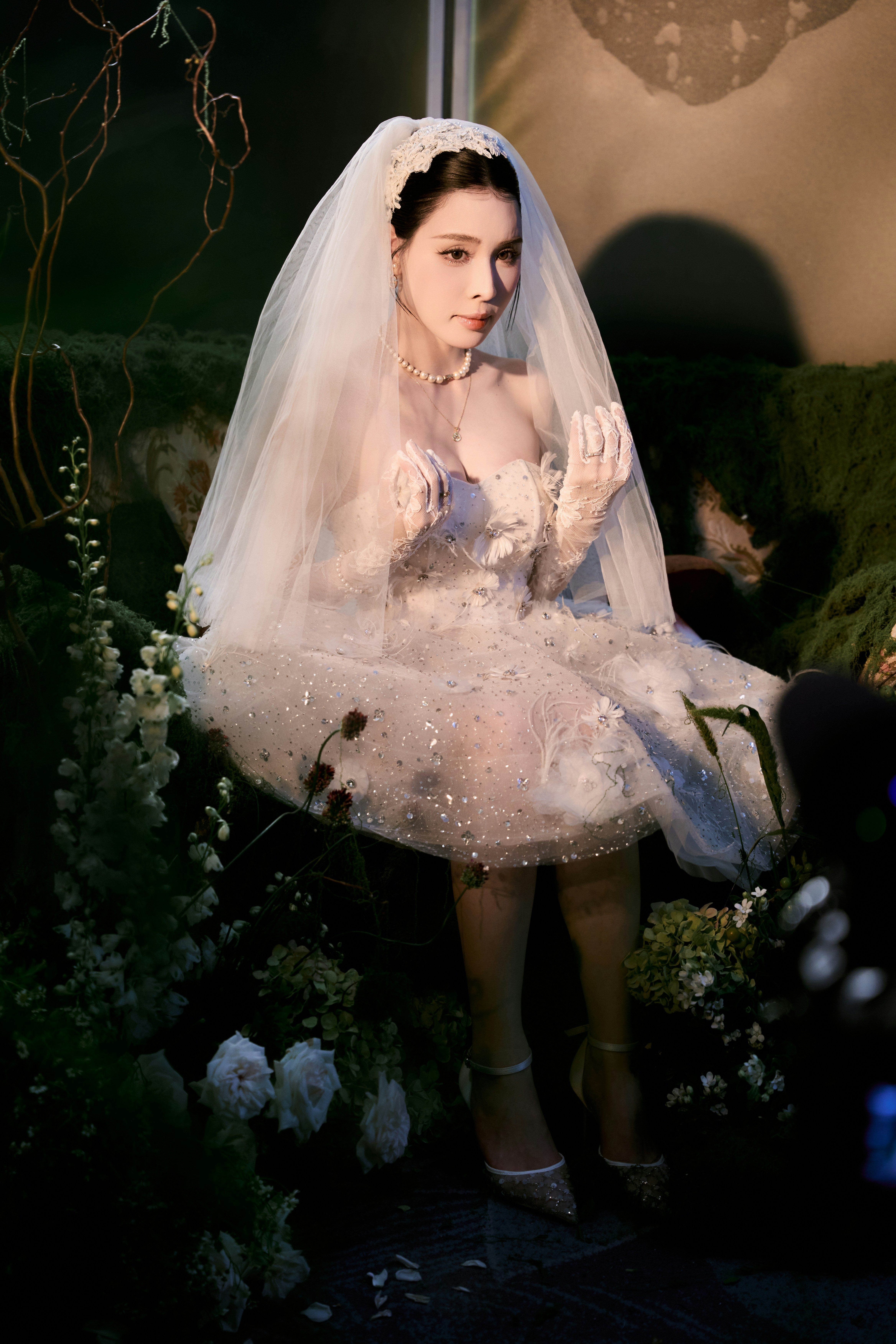 Woman in white wedding dress and veil among green plants