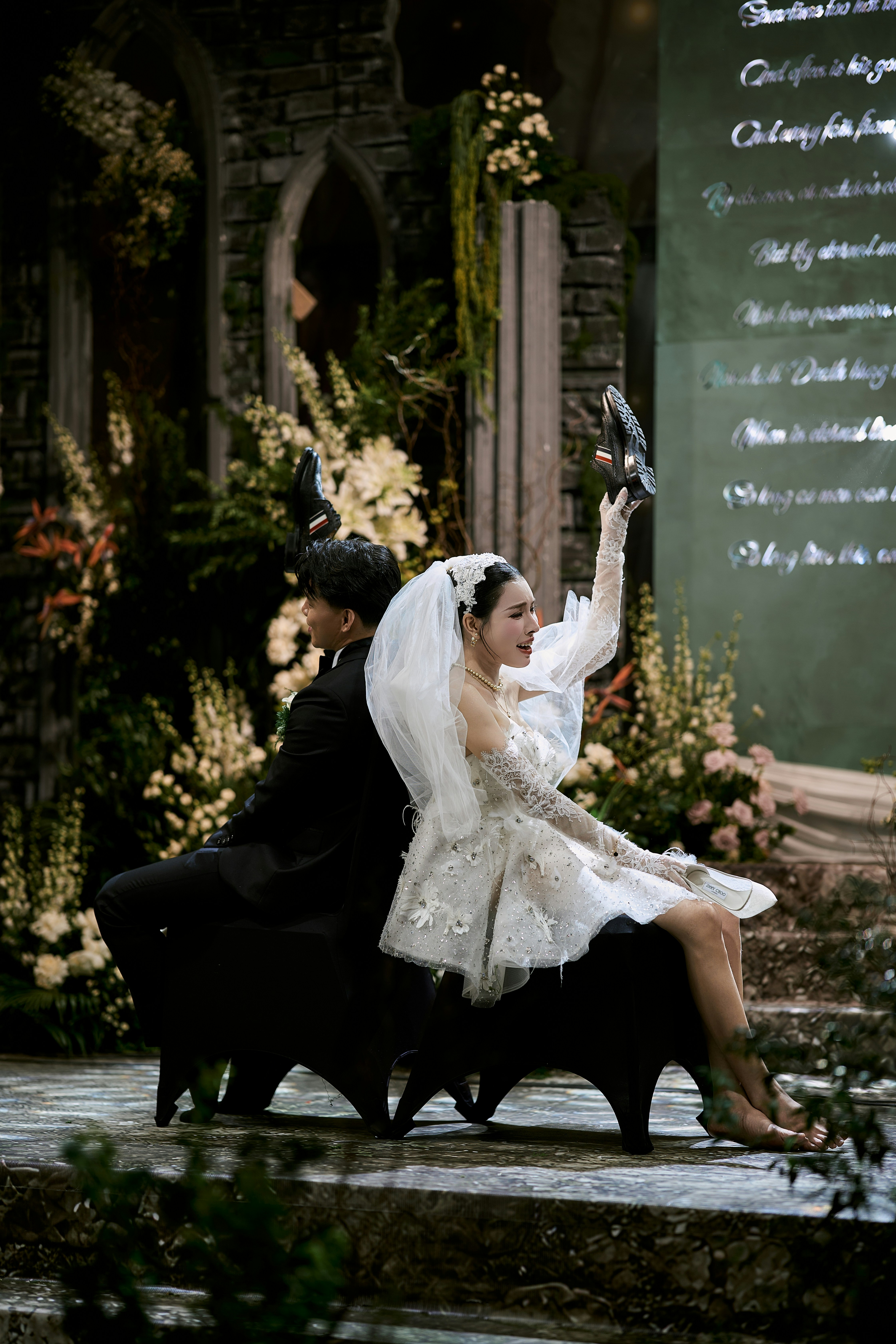 Bride and groom sit back-to-back on a decorated stage