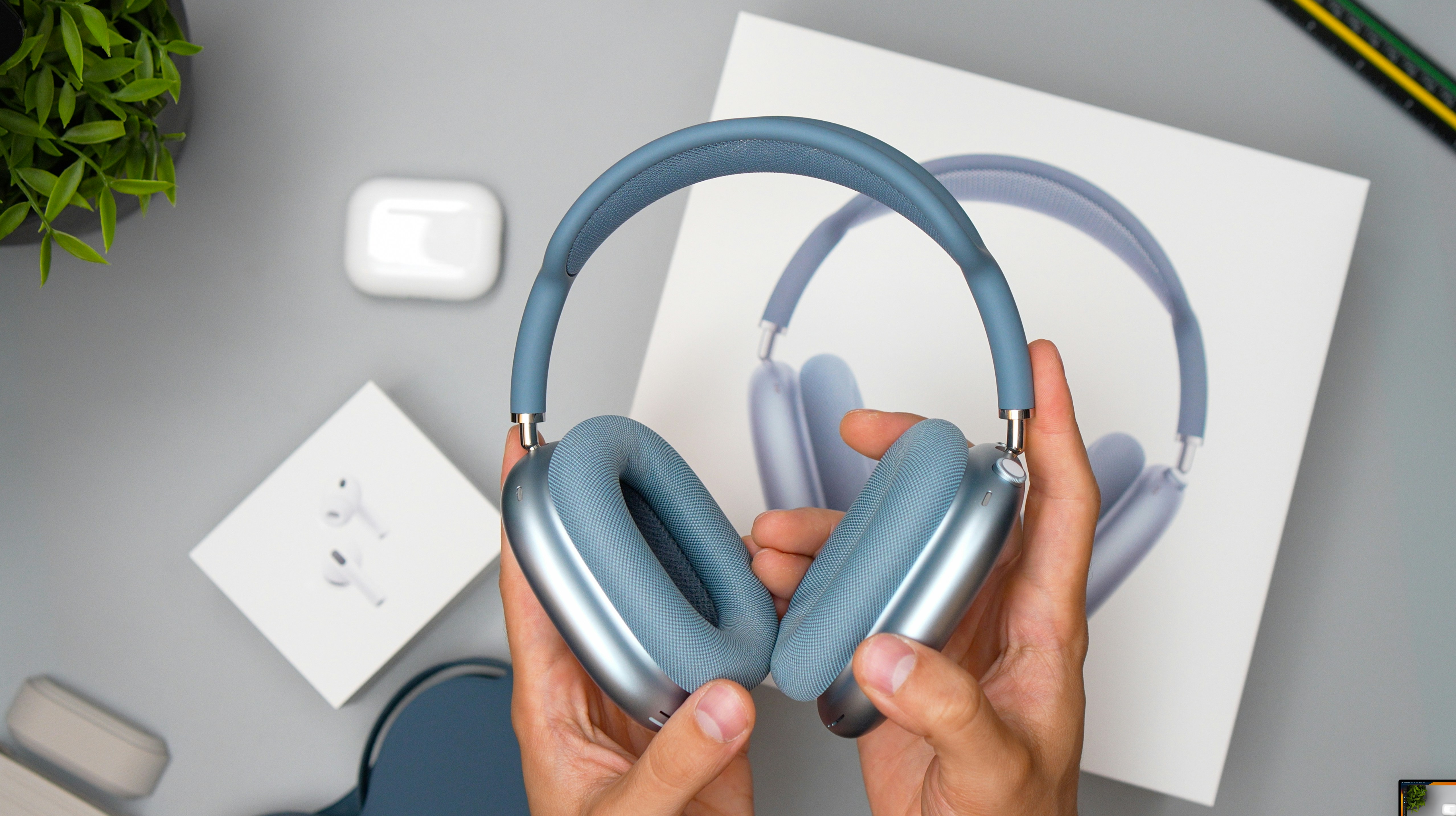 Hands holding blue over-ear headphones and product packaging.