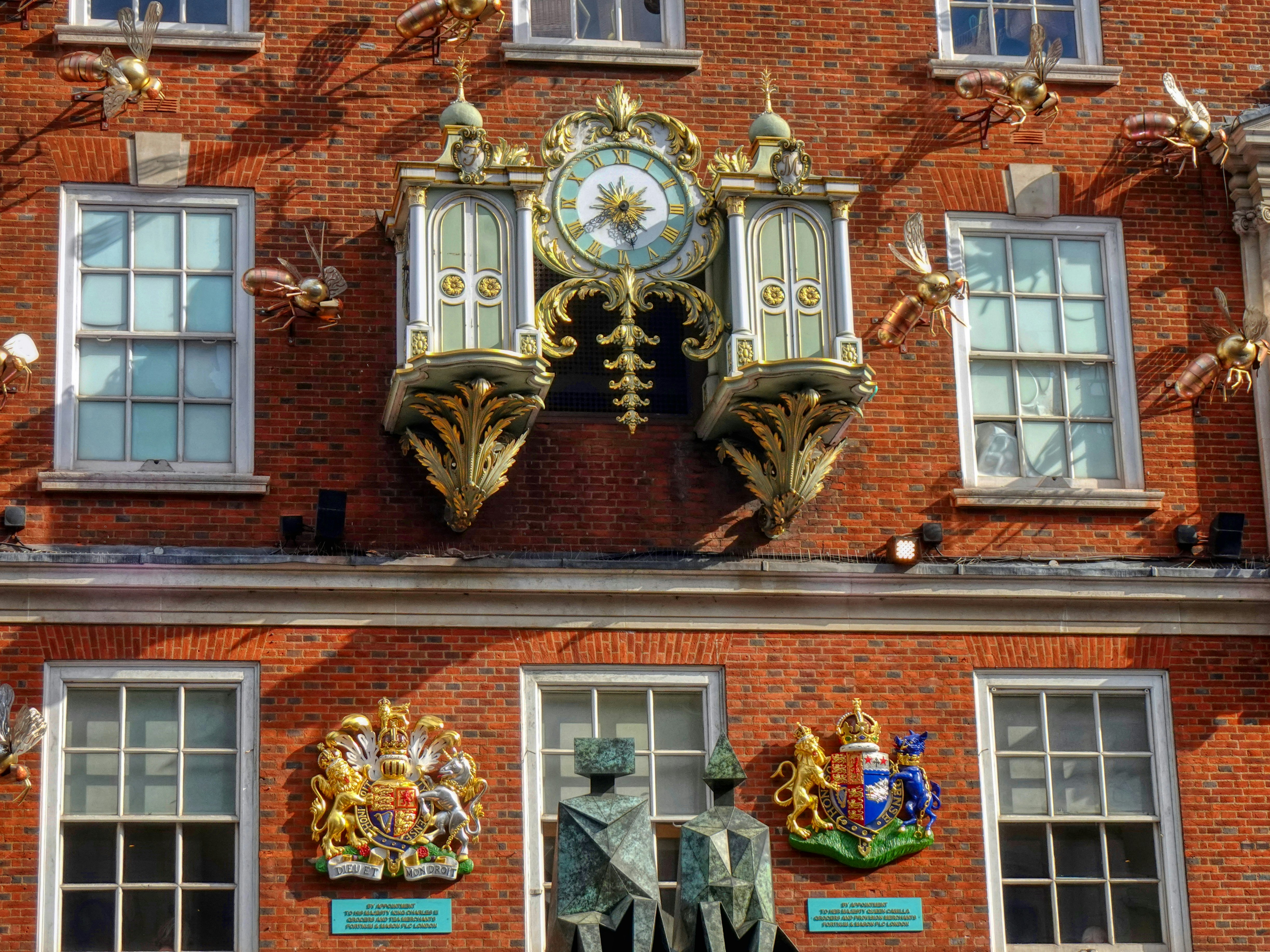 An ornate golden clock on a red brick building facade.