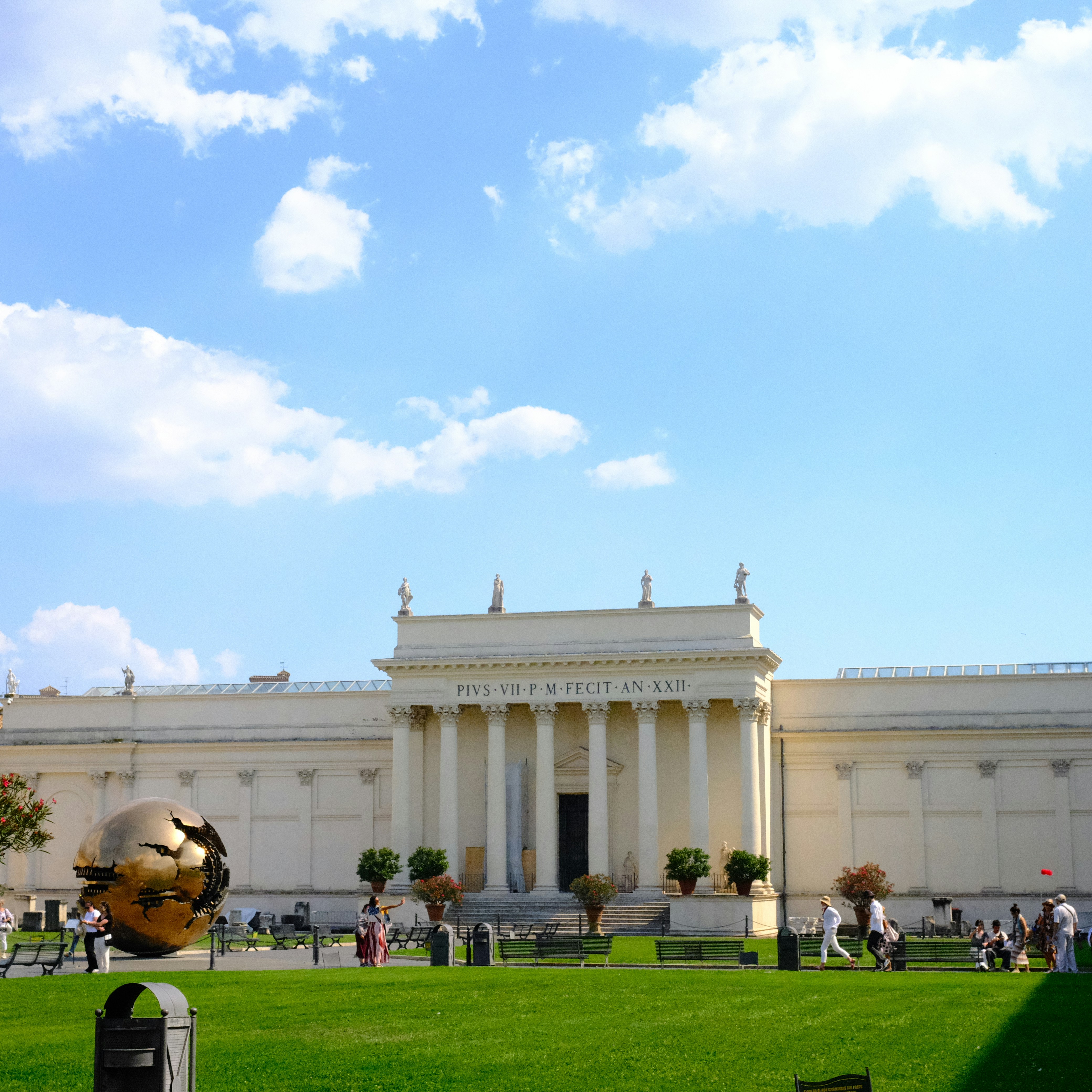 A classical building with golden sphere and green lawn.