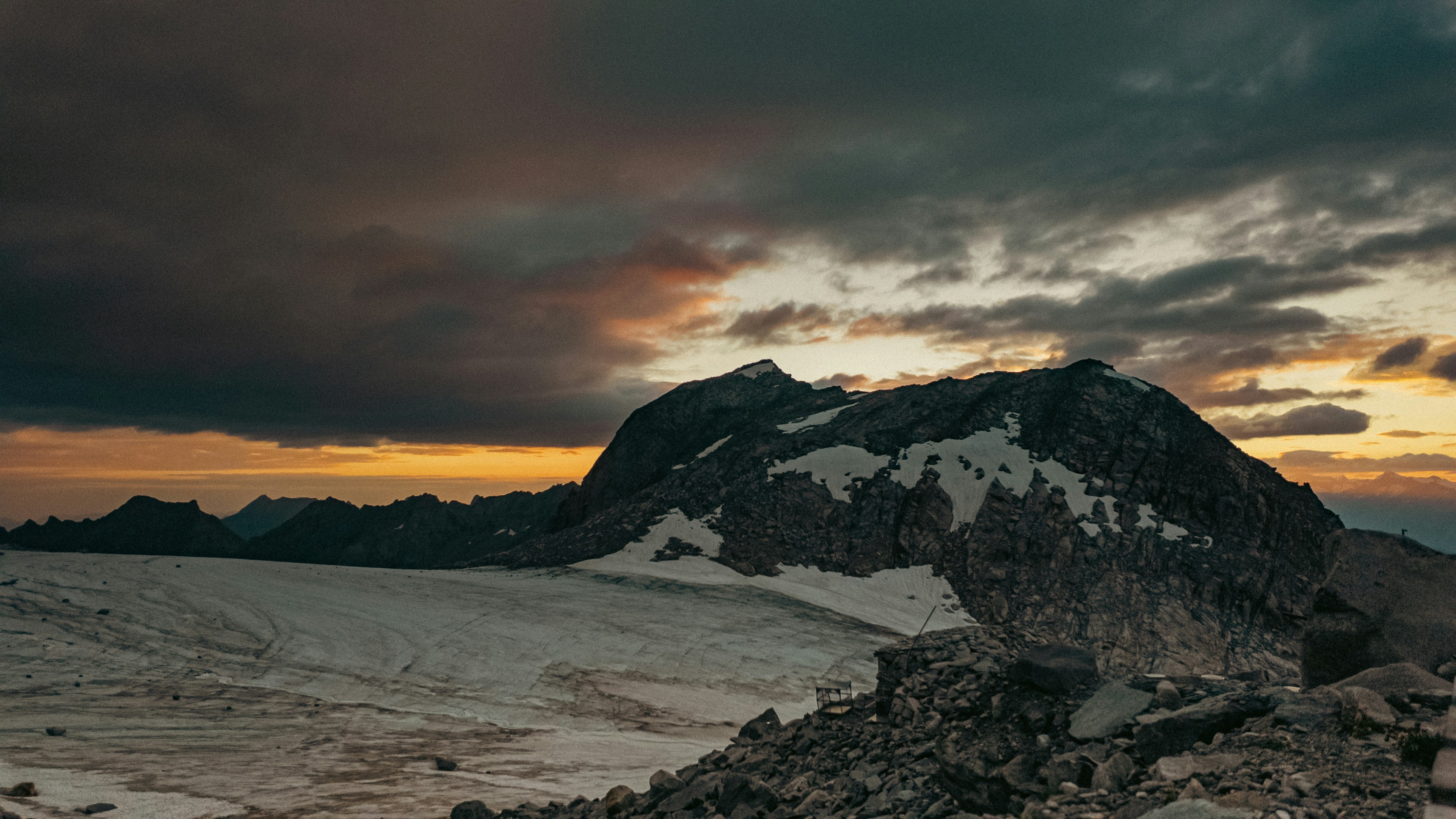 Dramatic mountain landscape with snow and a vibrant sunset sky.