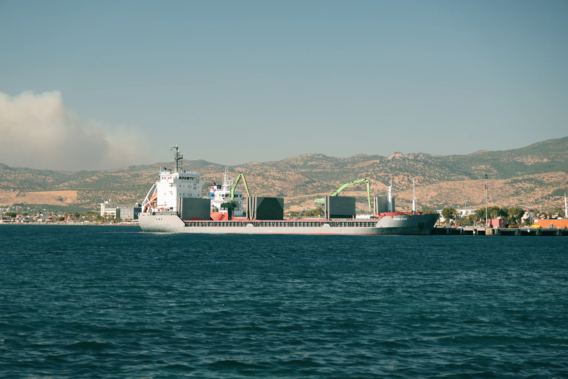 Cargo ship docked in a harbor with distant hills