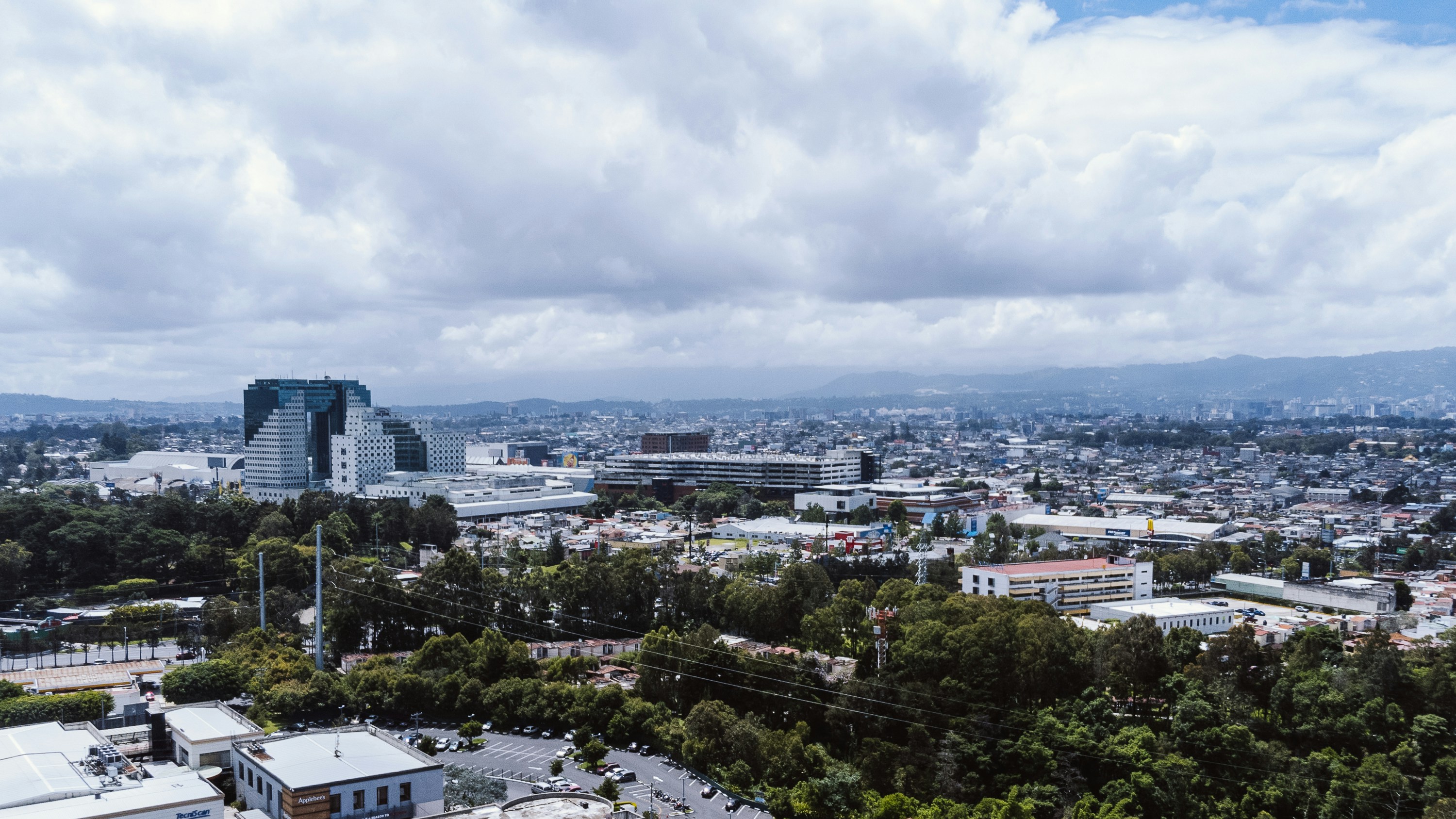 Urban landscape with buildings, lush trees, and an overcast sky