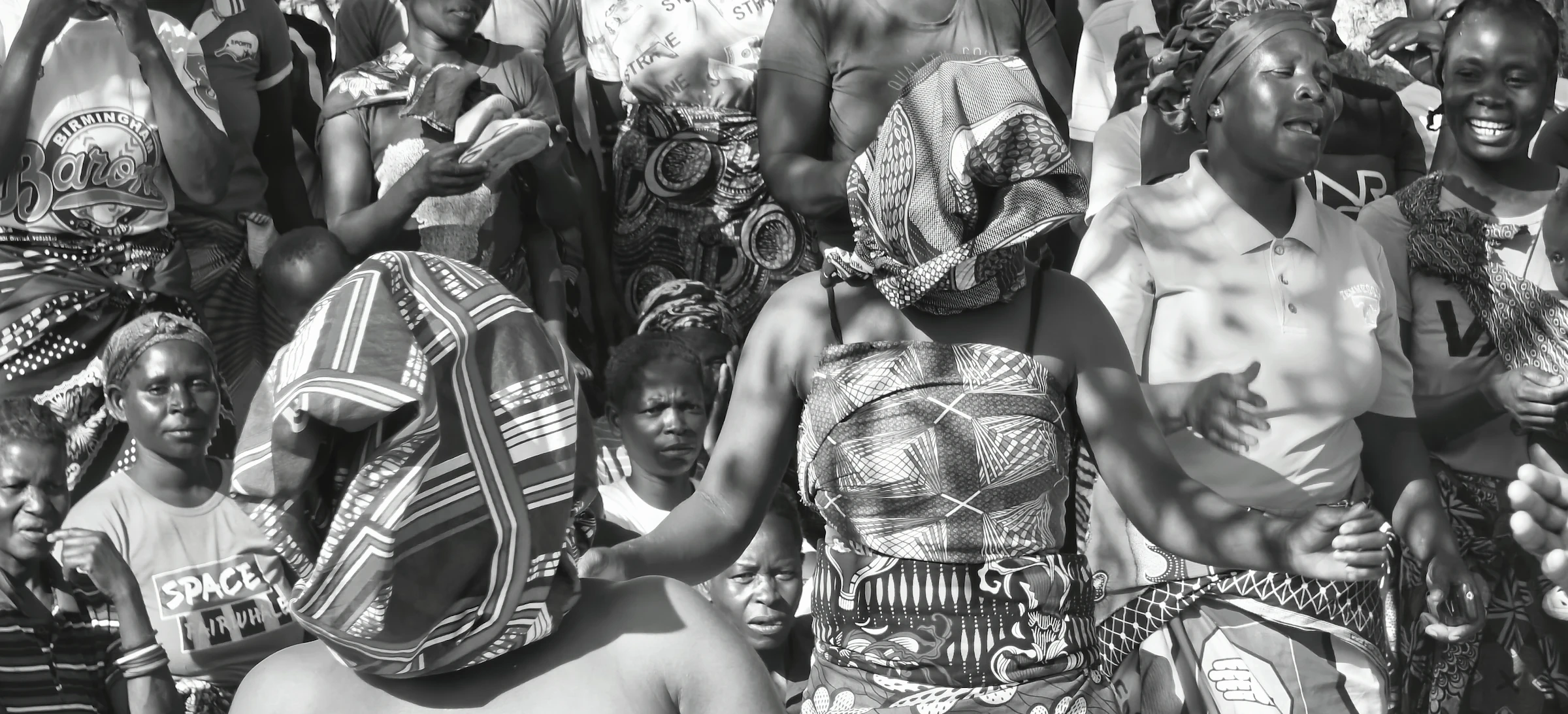 A crowd of women in patterned clothing and headwraps at a community gathering.