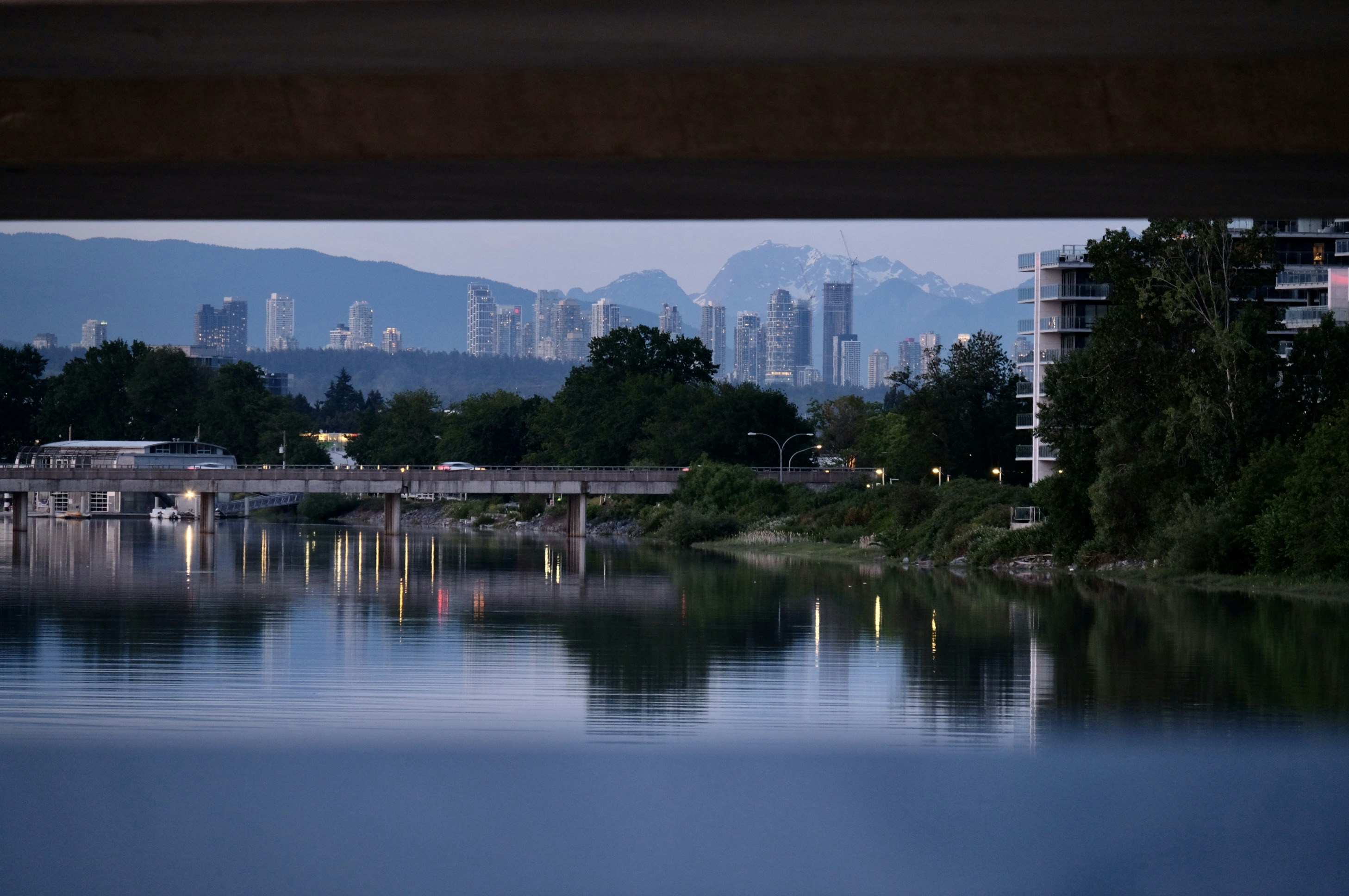 City skyline and mountains reflected in water at dusk