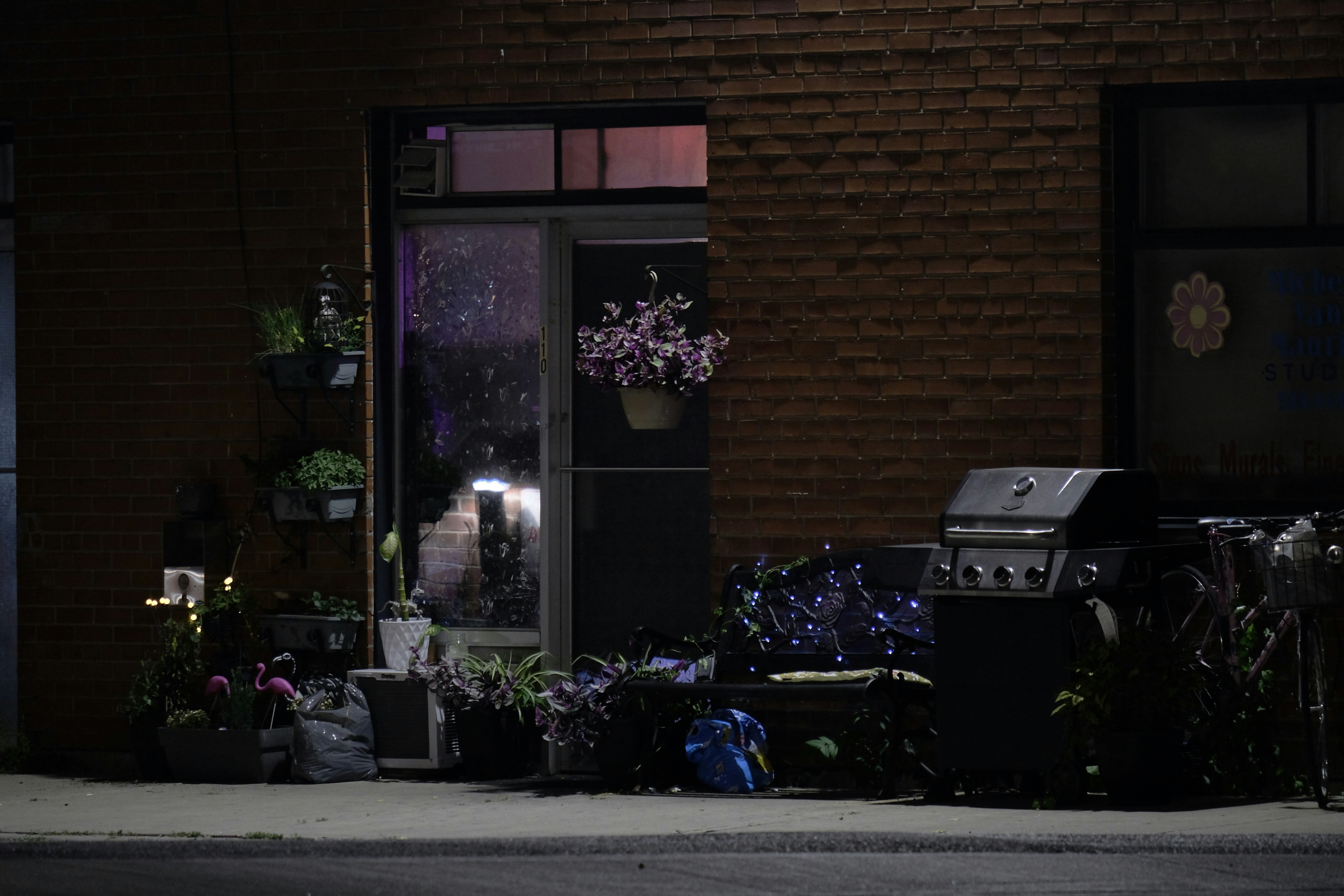 An outdoor patio with plants and a grill at night