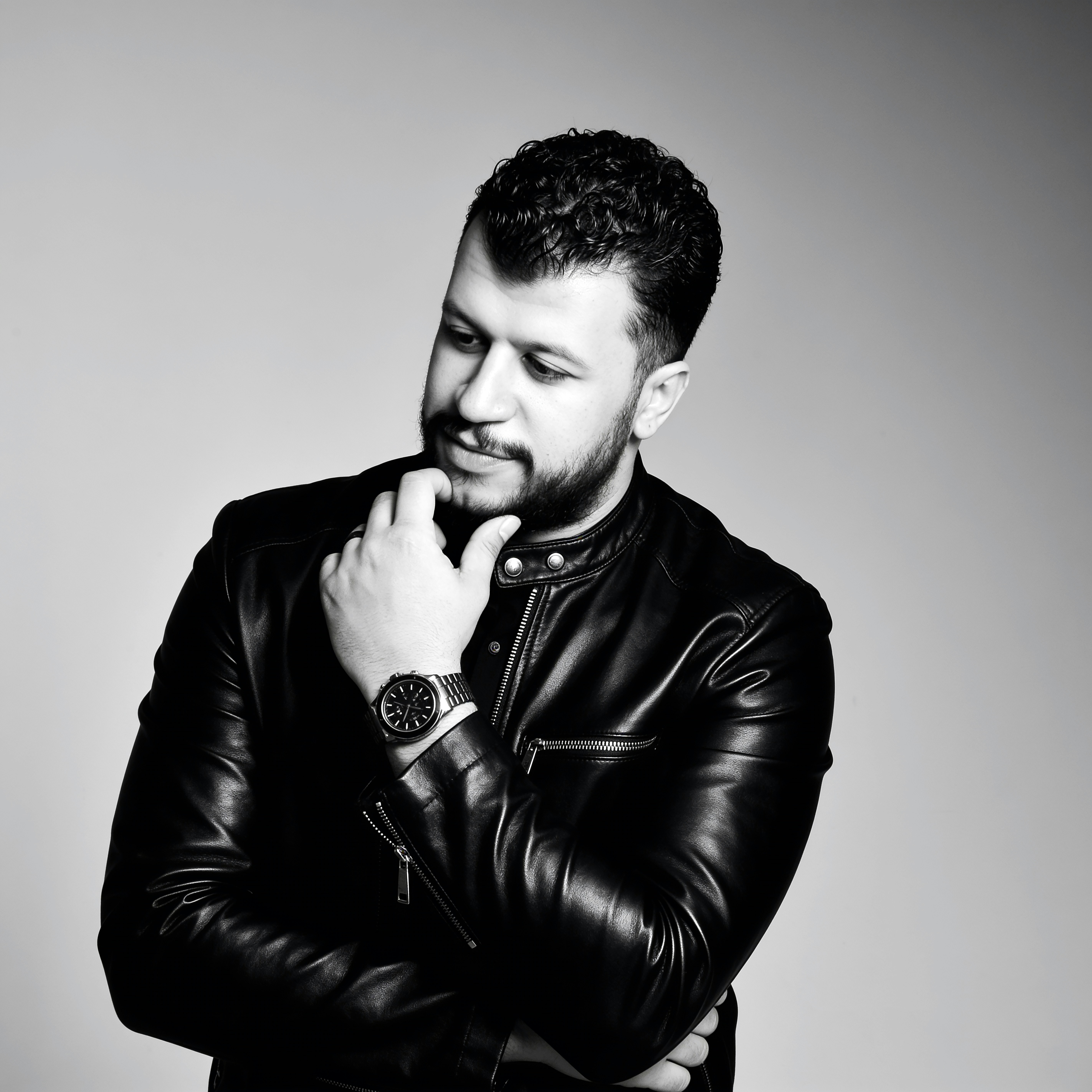 A man in a leather jacket looking down thoughtfully.
