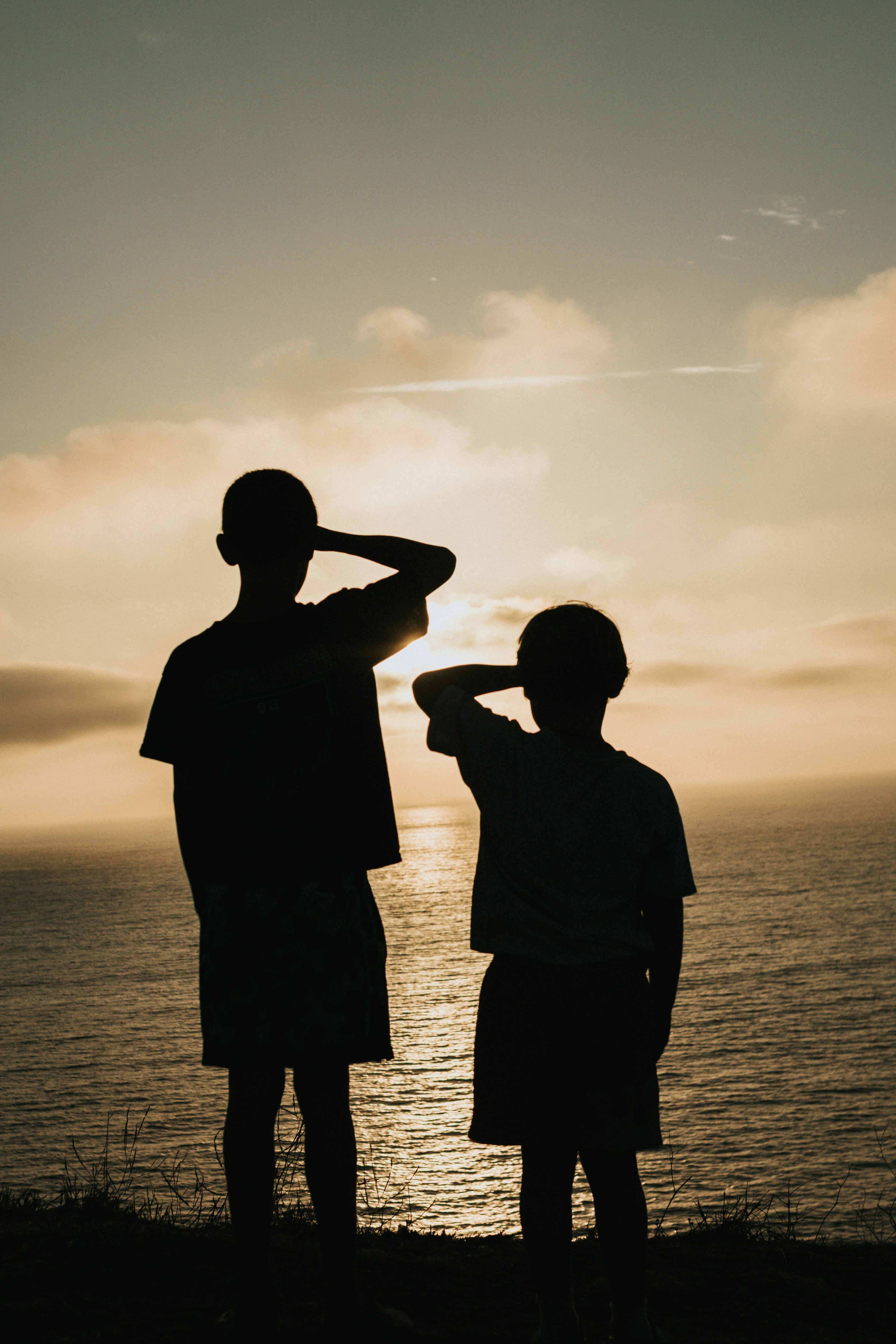 Two children silhouetted against a vibrant sunset over the ocean. - 相关推荐