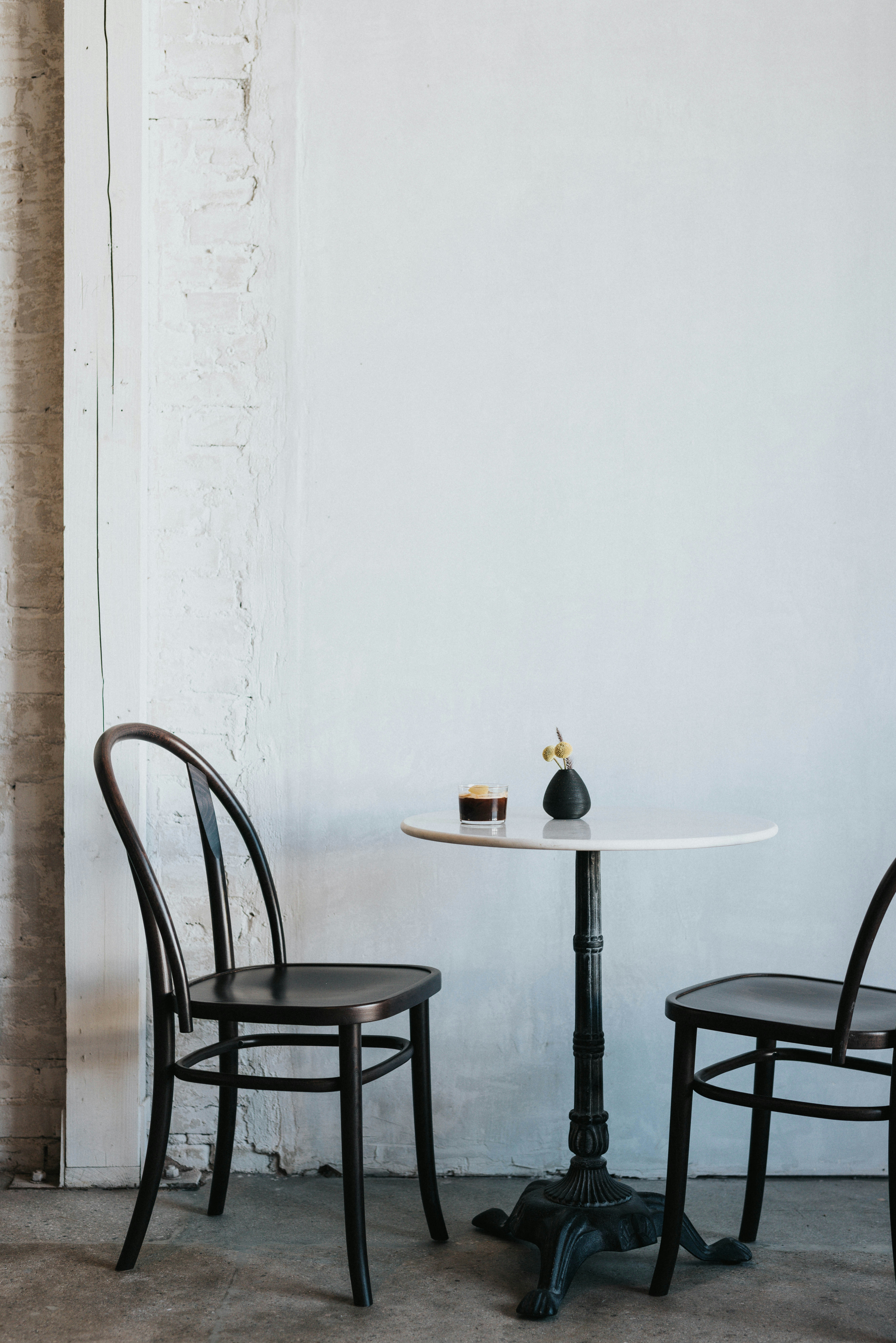 Two chairs and a small table against a white wall.