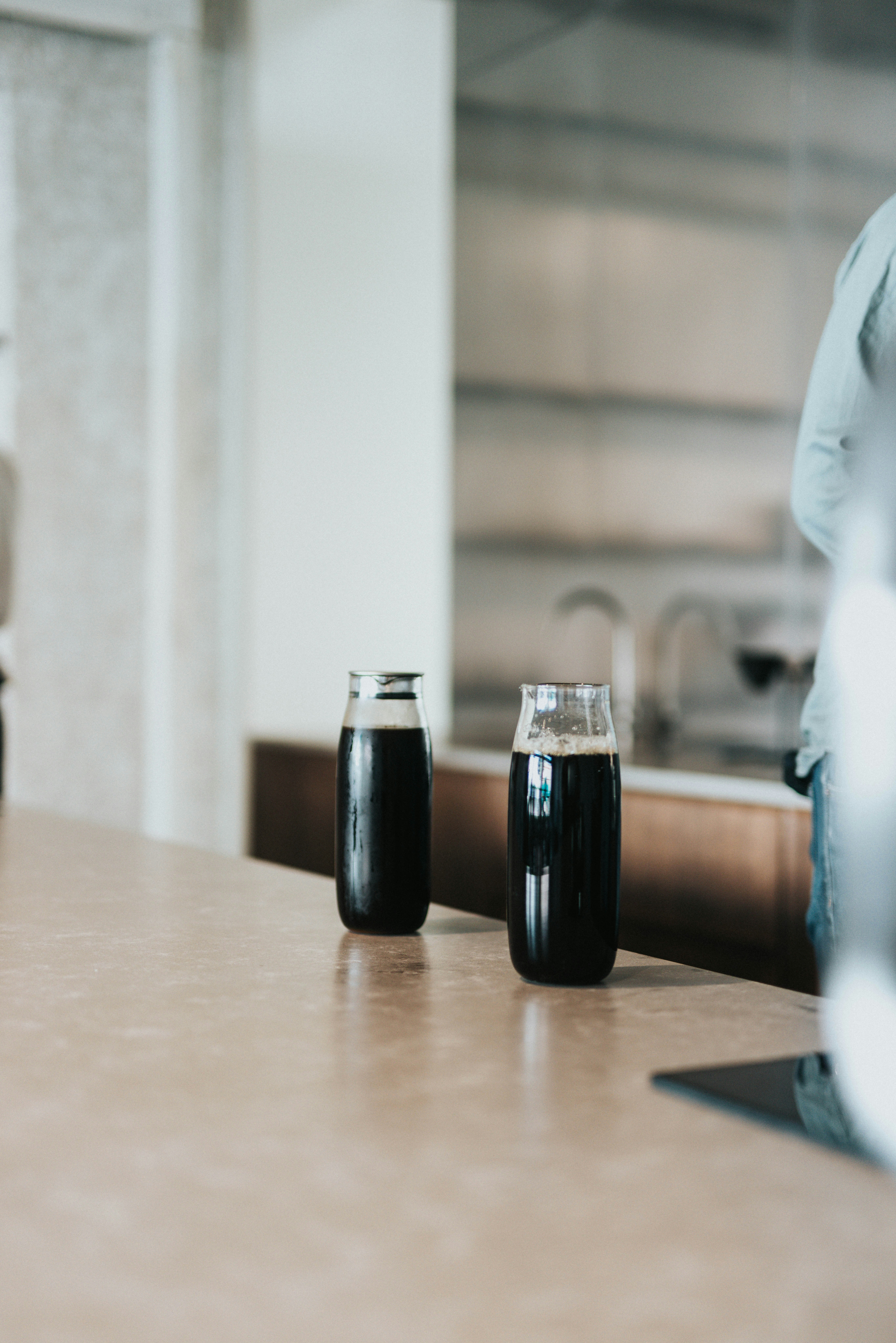 Two dark drinks in glasses on a kitchen counter
