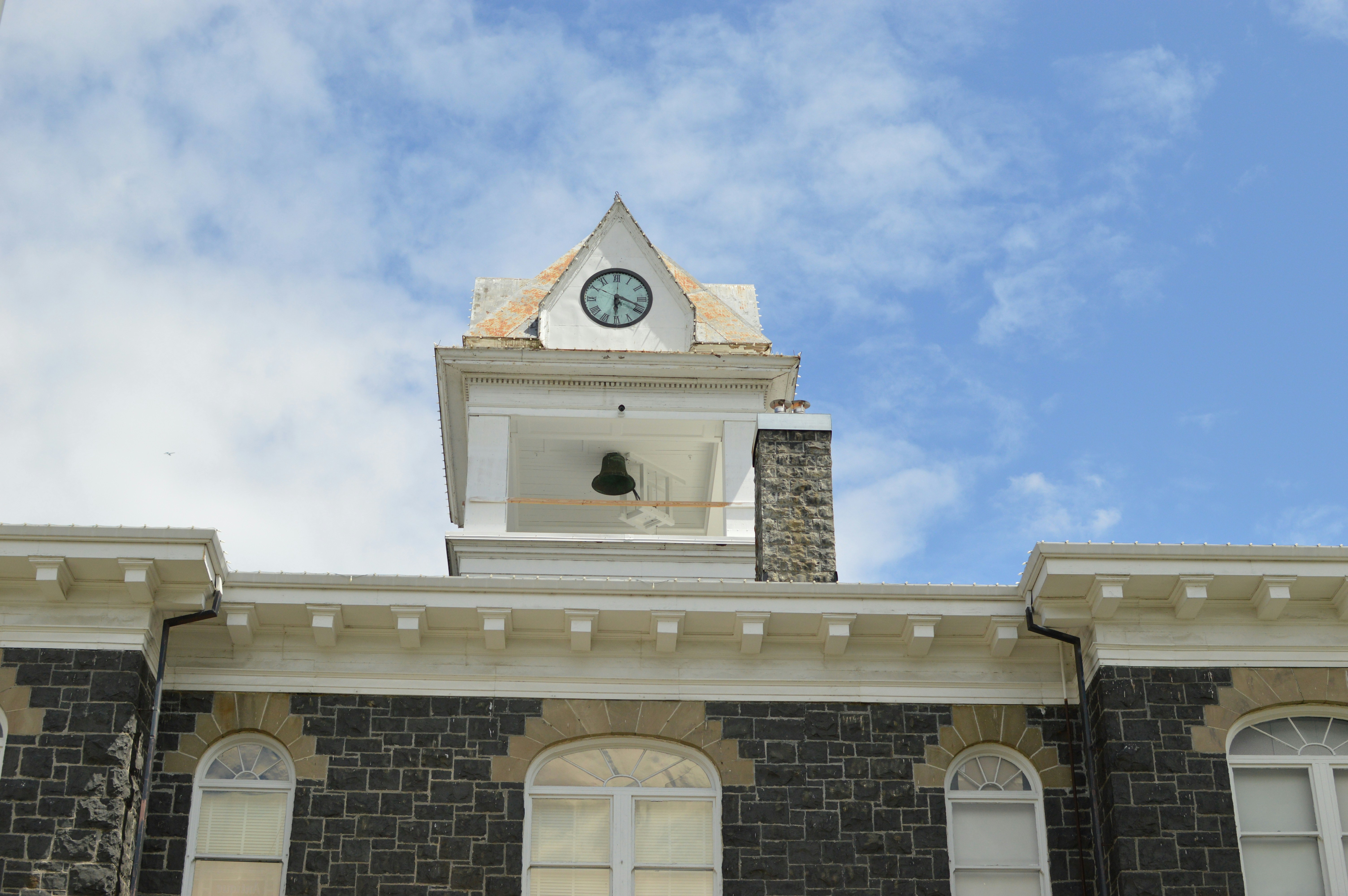 White clock tower above a bluestone building