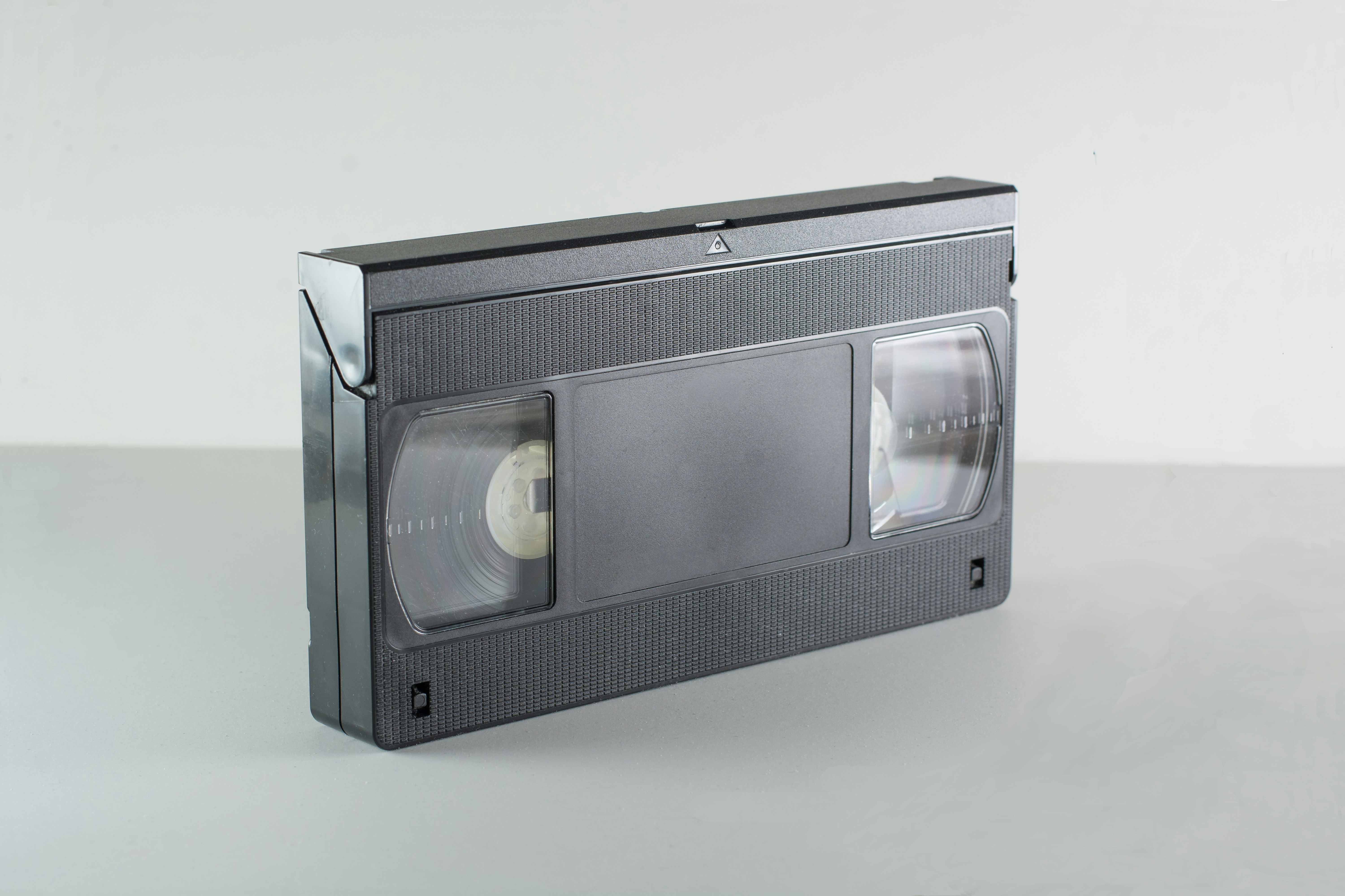 A black vhs video cassette tape on a grey surface