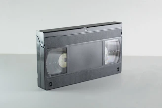 A black vhs video cassette tape on a grey surface.